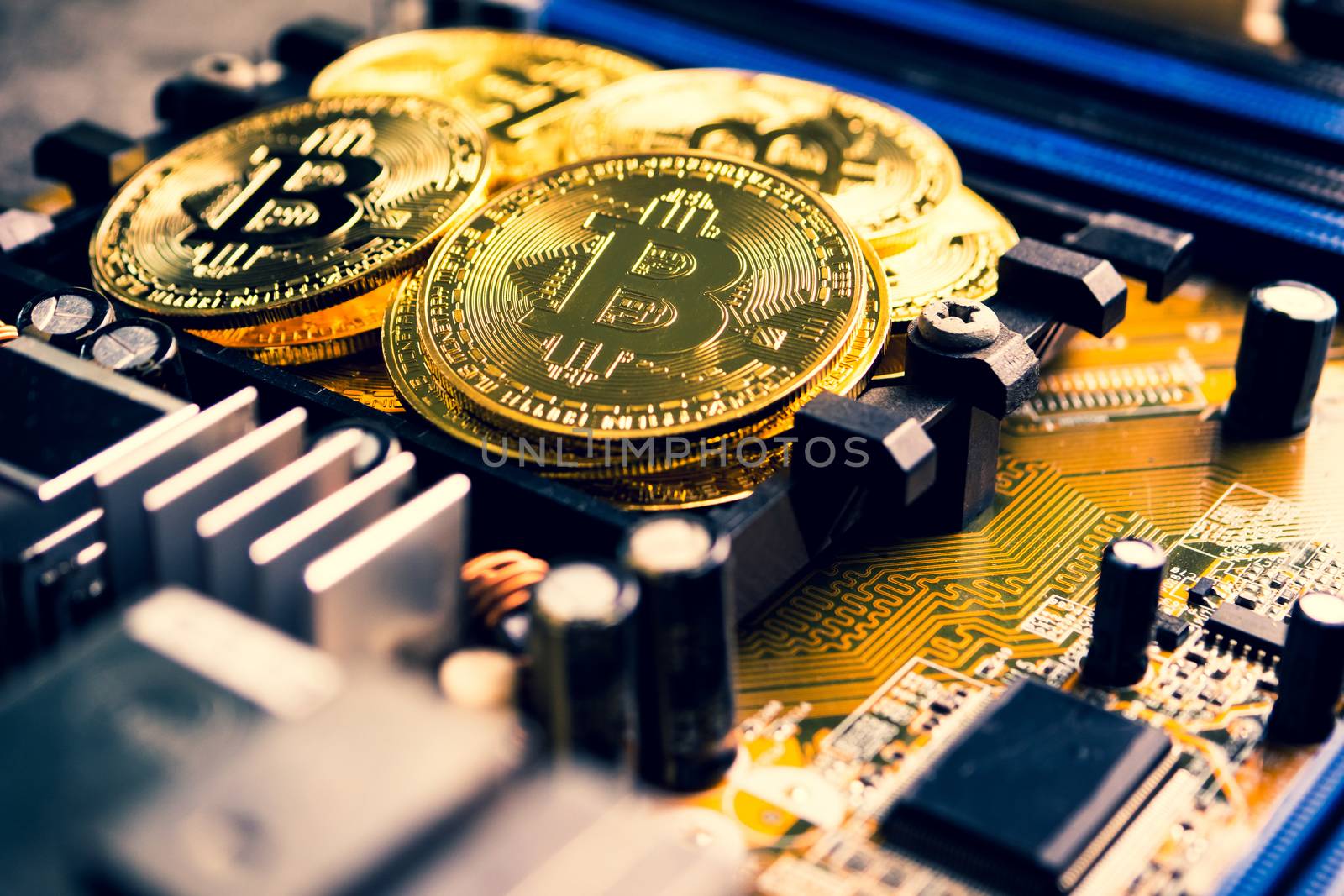 Golden coins with bitcoin symbol on a mainboard.