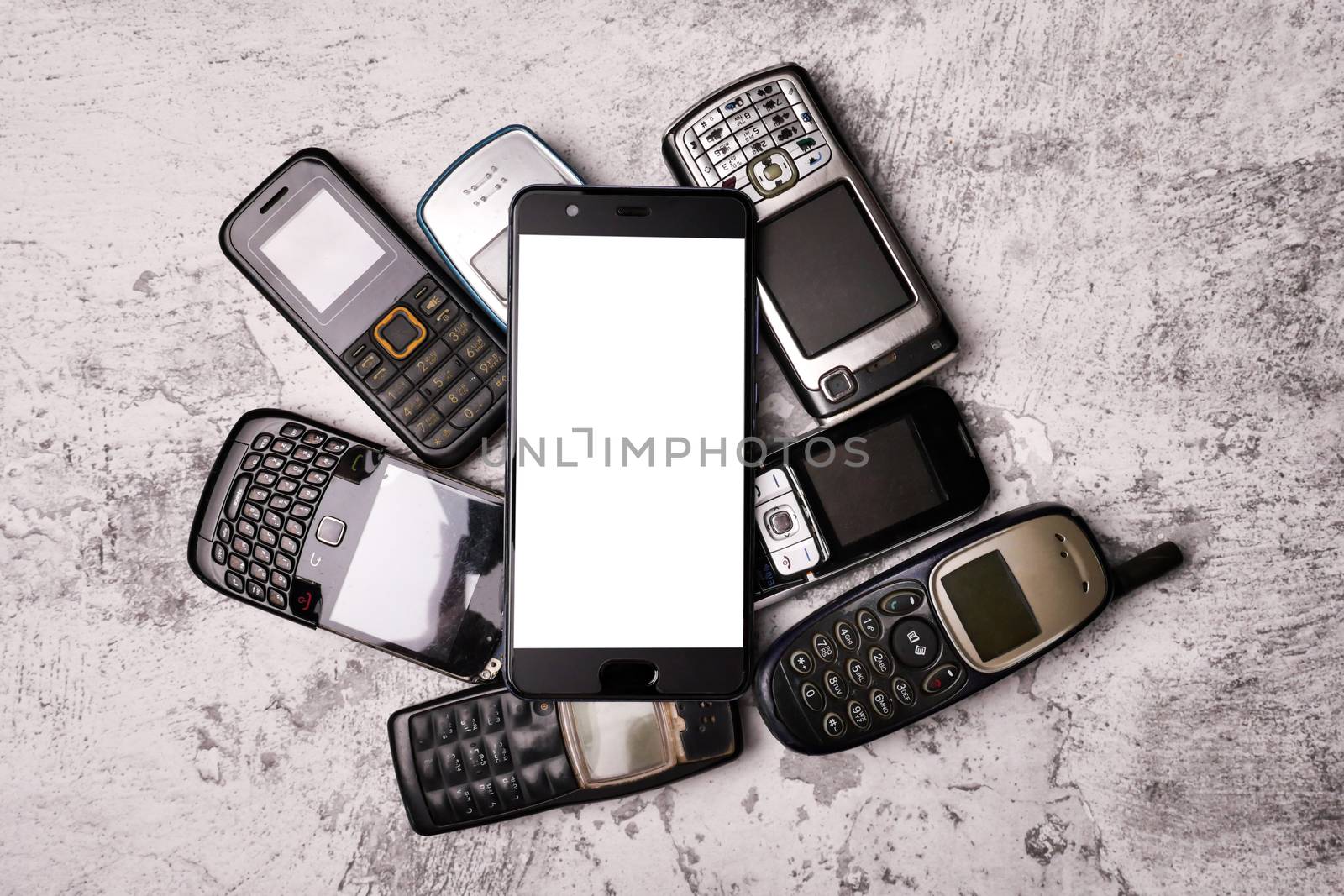 Many obsoleted cellphones and a smartphone on a grunge background.