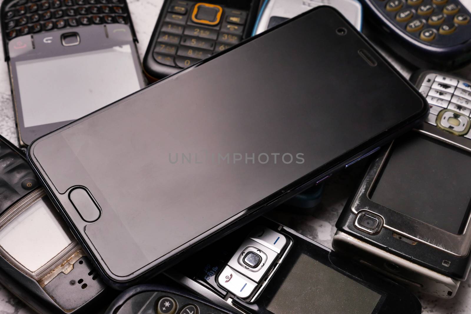 A smartphone on pile of obsoleted cellphones. by ronnarong