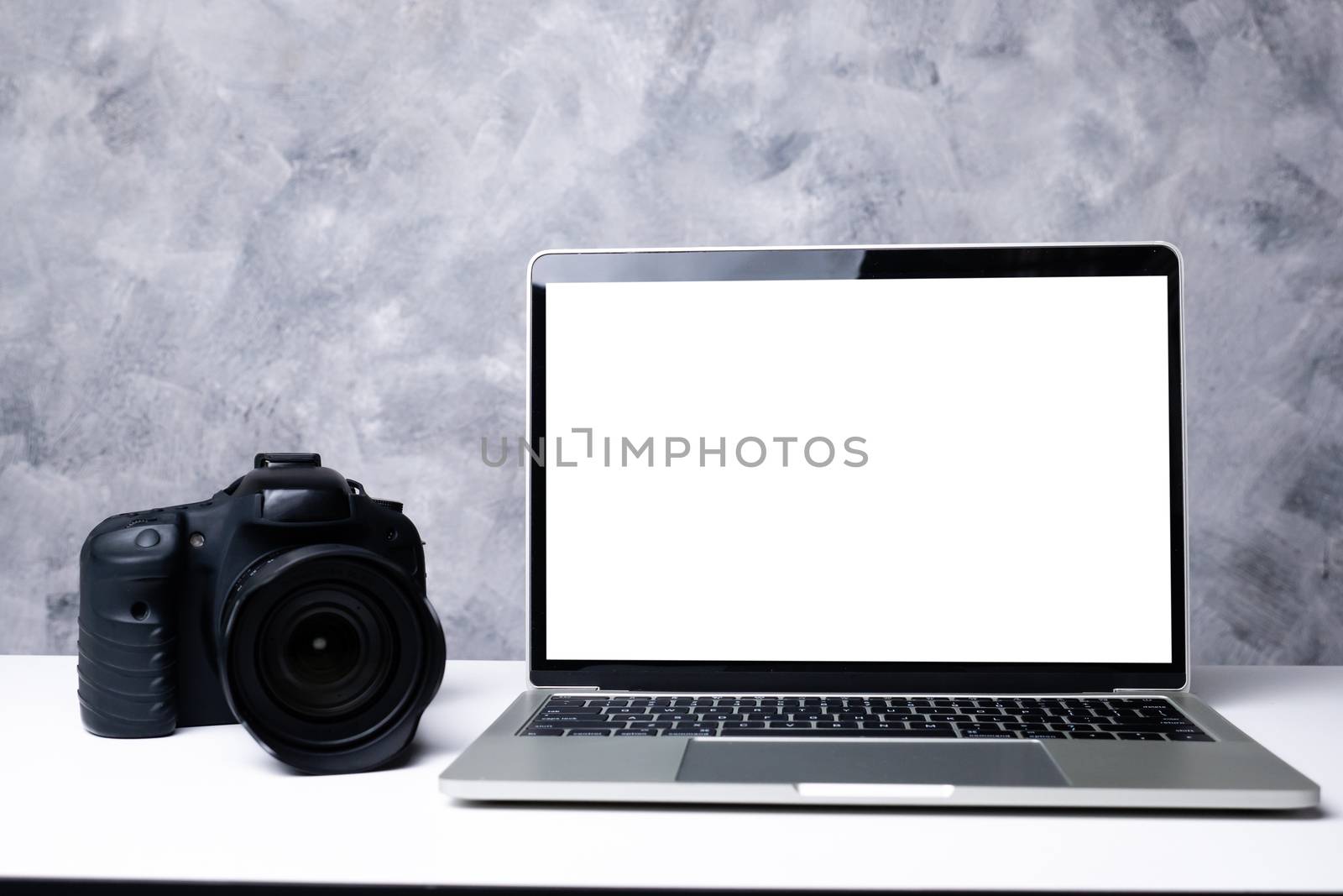 A black digital camera and a computer laptop on a table  by ronnarong