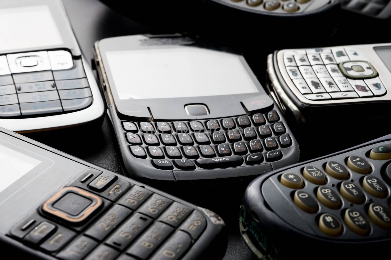 Old and obsoleted cellphones on a black background.