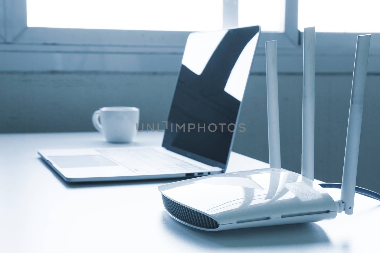 Laptop computer and router device on the table by ronnarong