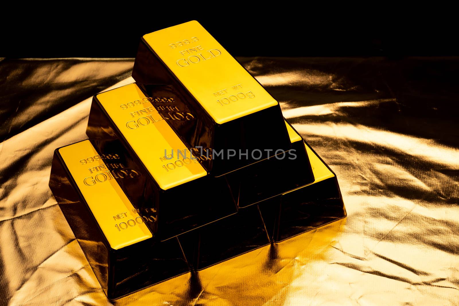 Stack of gold bars on shiny yellow background.