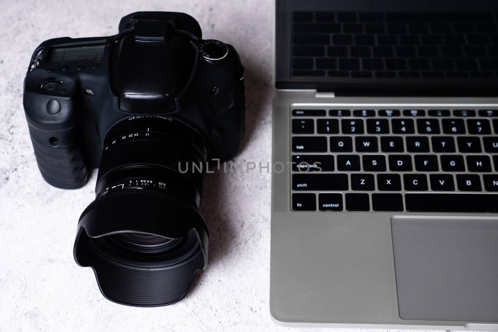 A black digital camera and a computer laptop on a table.