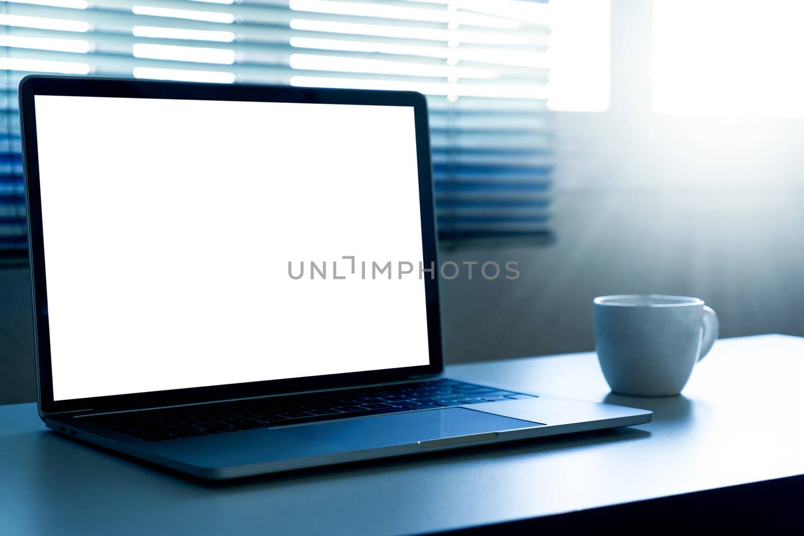 Blank screen laptop computer and a cup of coffee on the table
