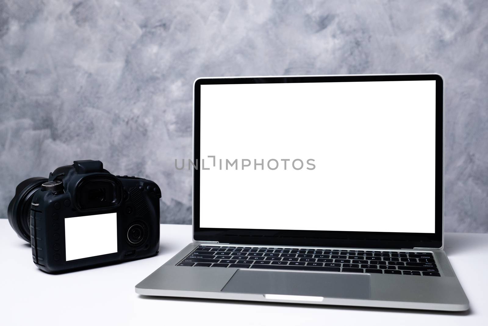 A black digital camera and a computer laptop on a table  by ronnarong
