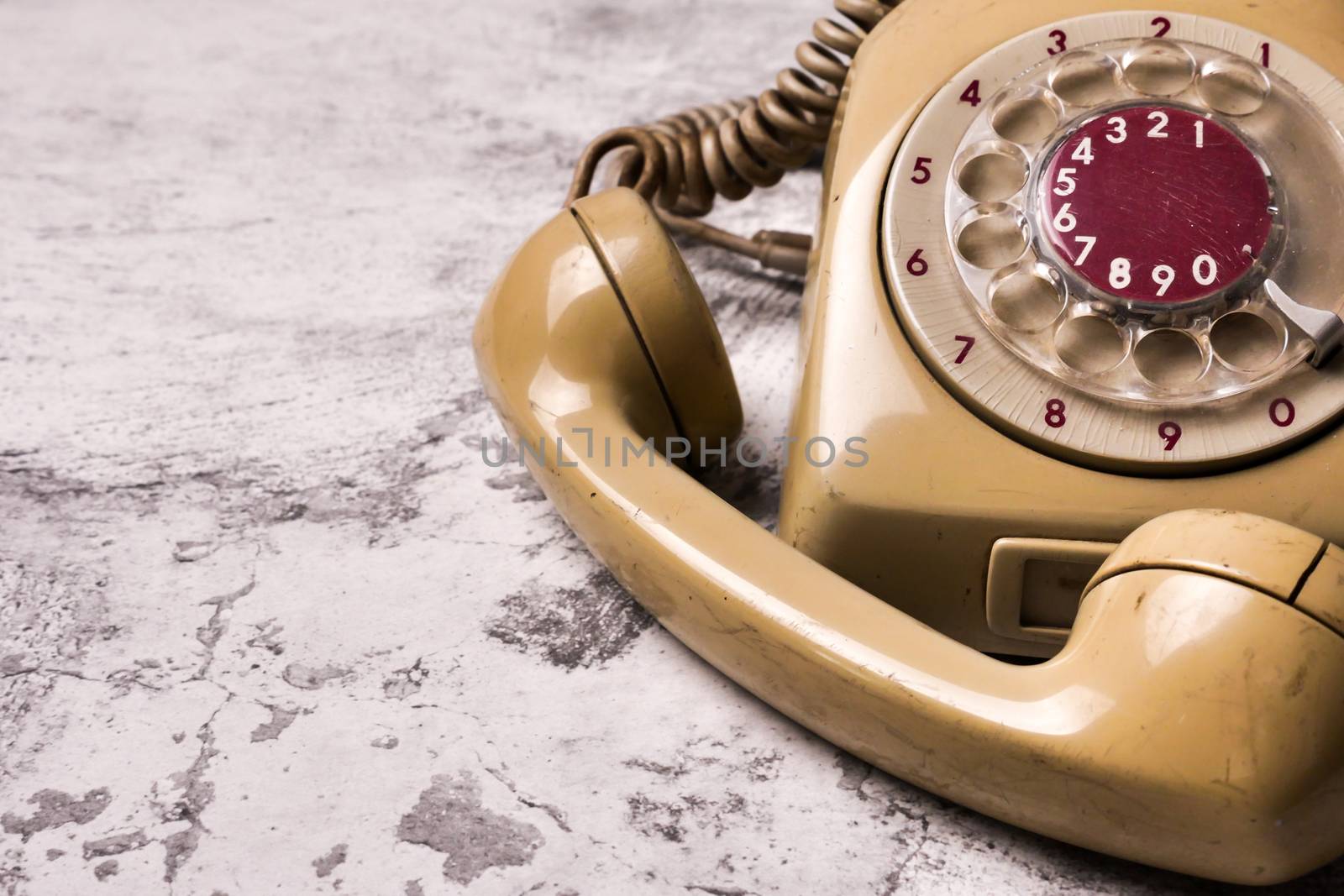 An old telephone with rotary dial on a grunge background.