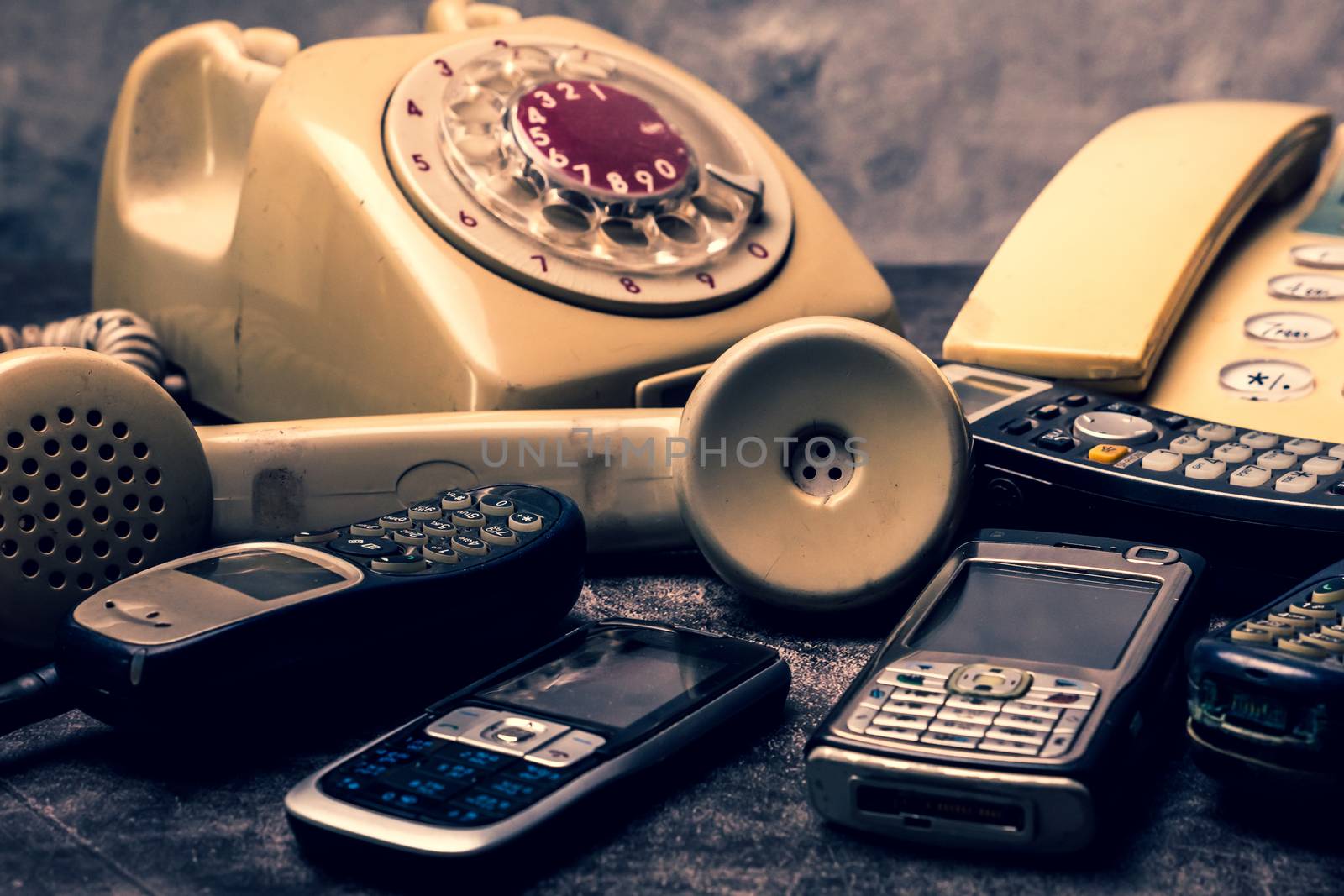 An old telephone with rotary dial, landline and obsoleted cellph by ronnarong