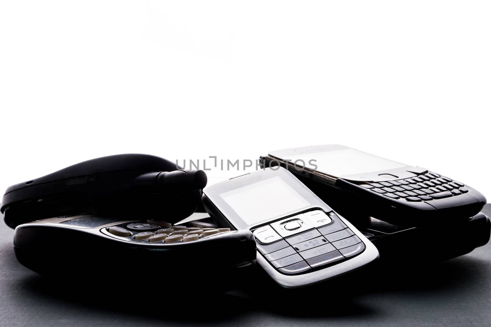 Old and obsoleted cellphones on a black background. by ronnarong