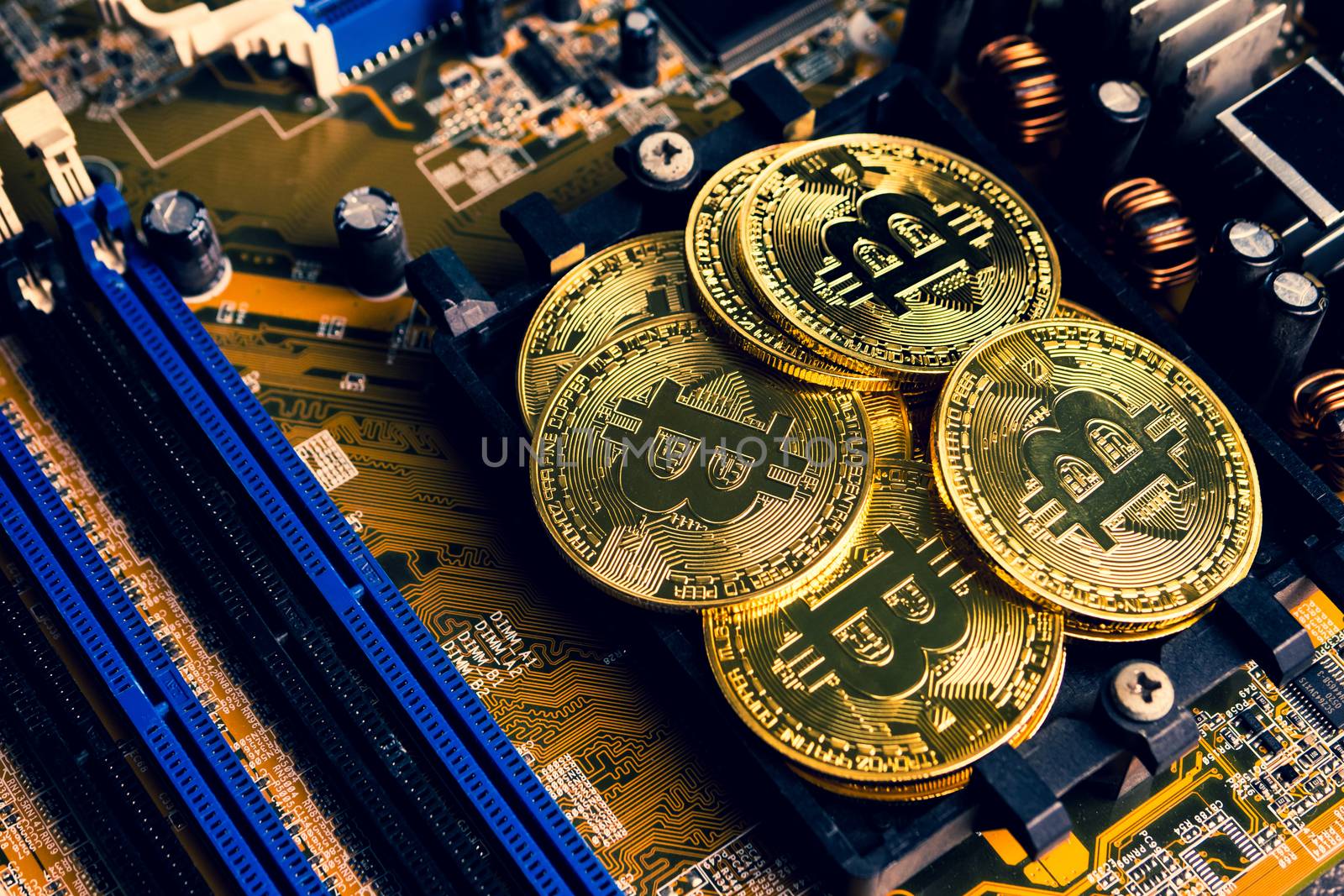 Golden coins with bitcoin symbol on a mainboard.