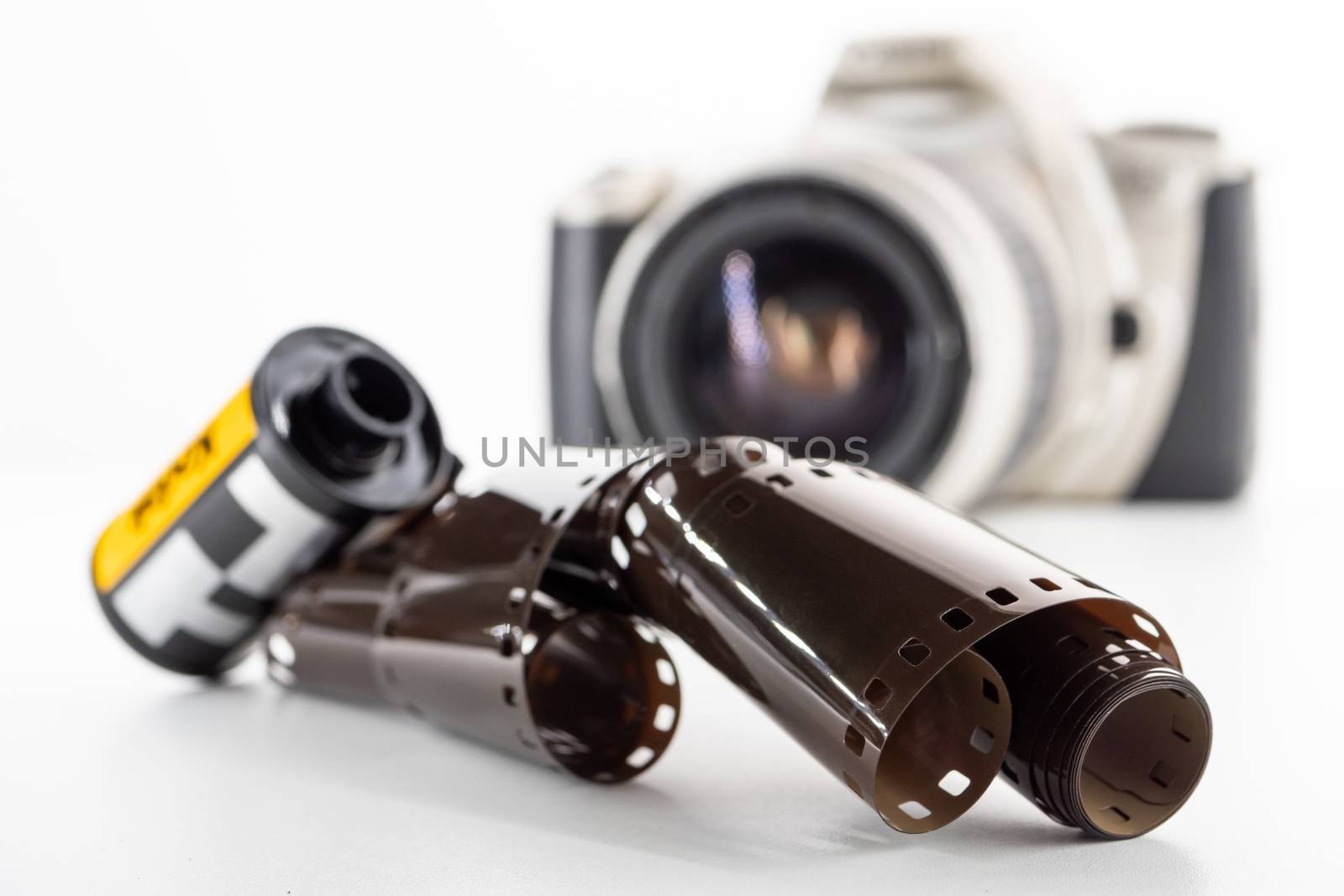 Single lens reflex camera and a film roll on a white background.