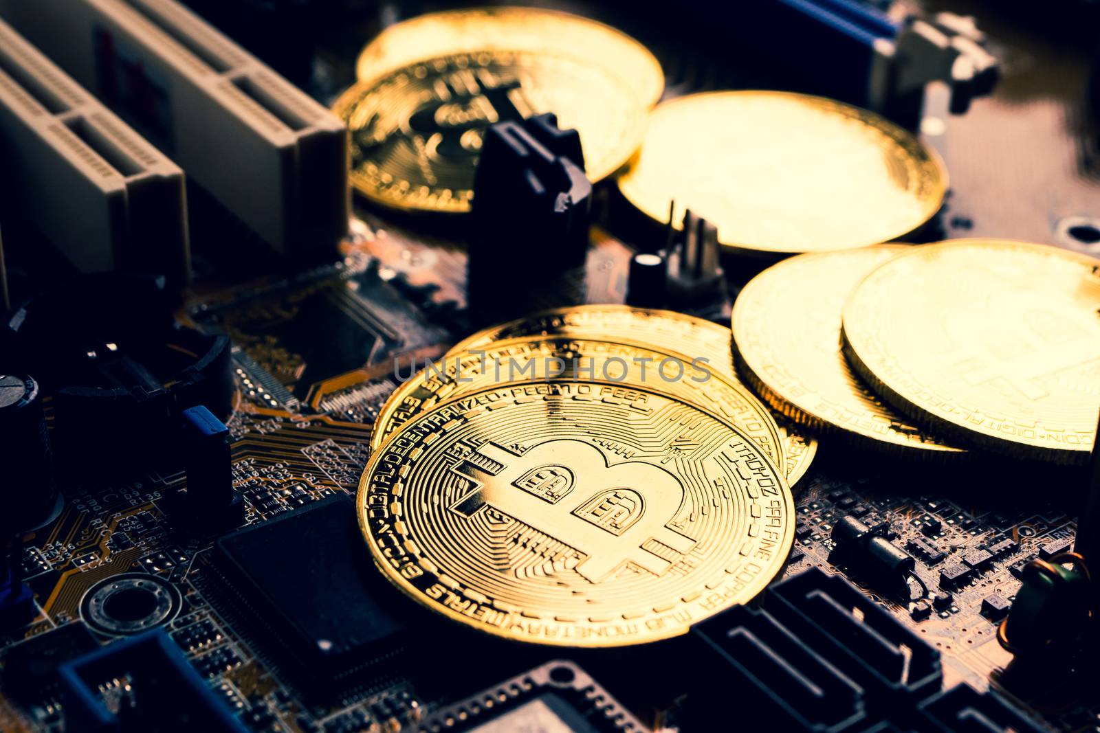 Golden coins with bitcoin symbol on a mainboard.