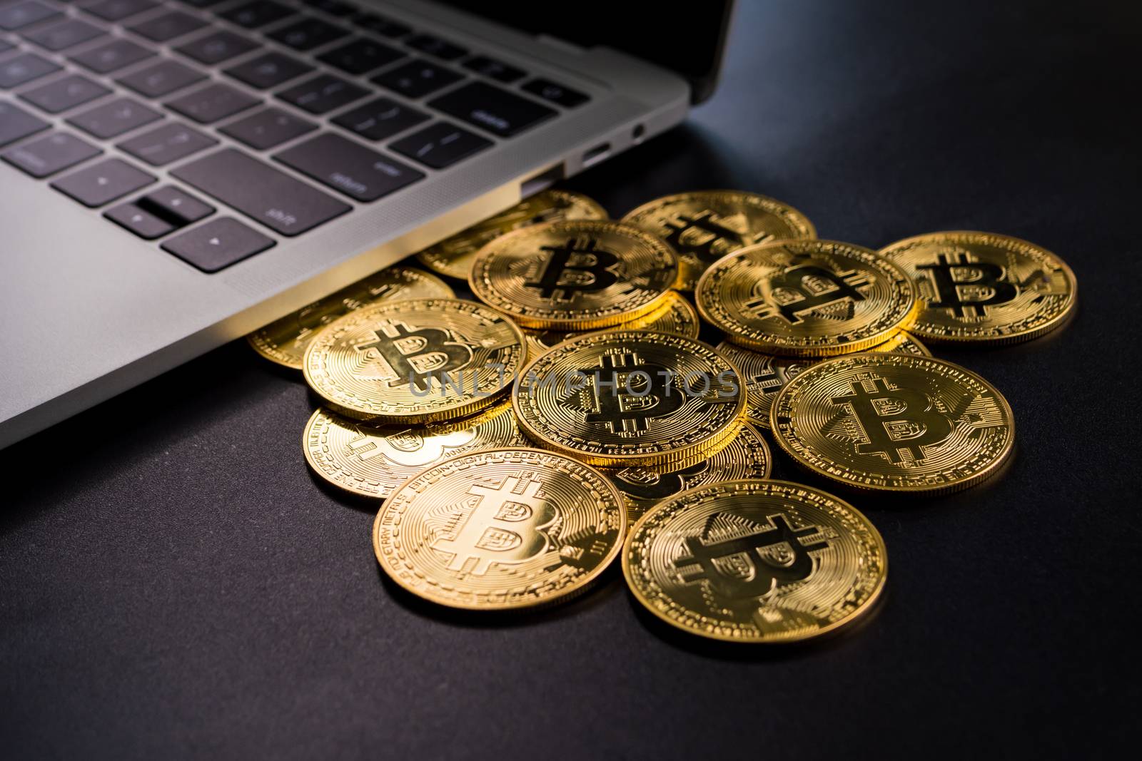 Computer and golden coins with bitcoin symbol on a black background.