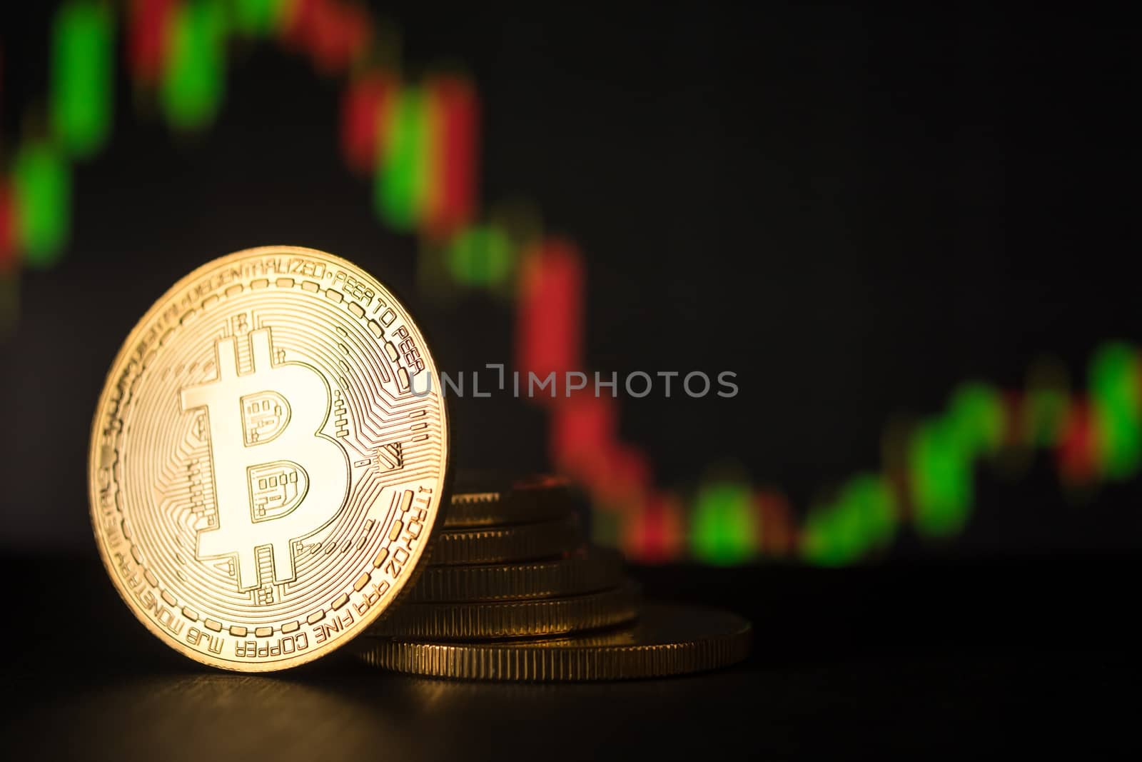 Stack of golden coins with bitcoin symbol with stock graph background.