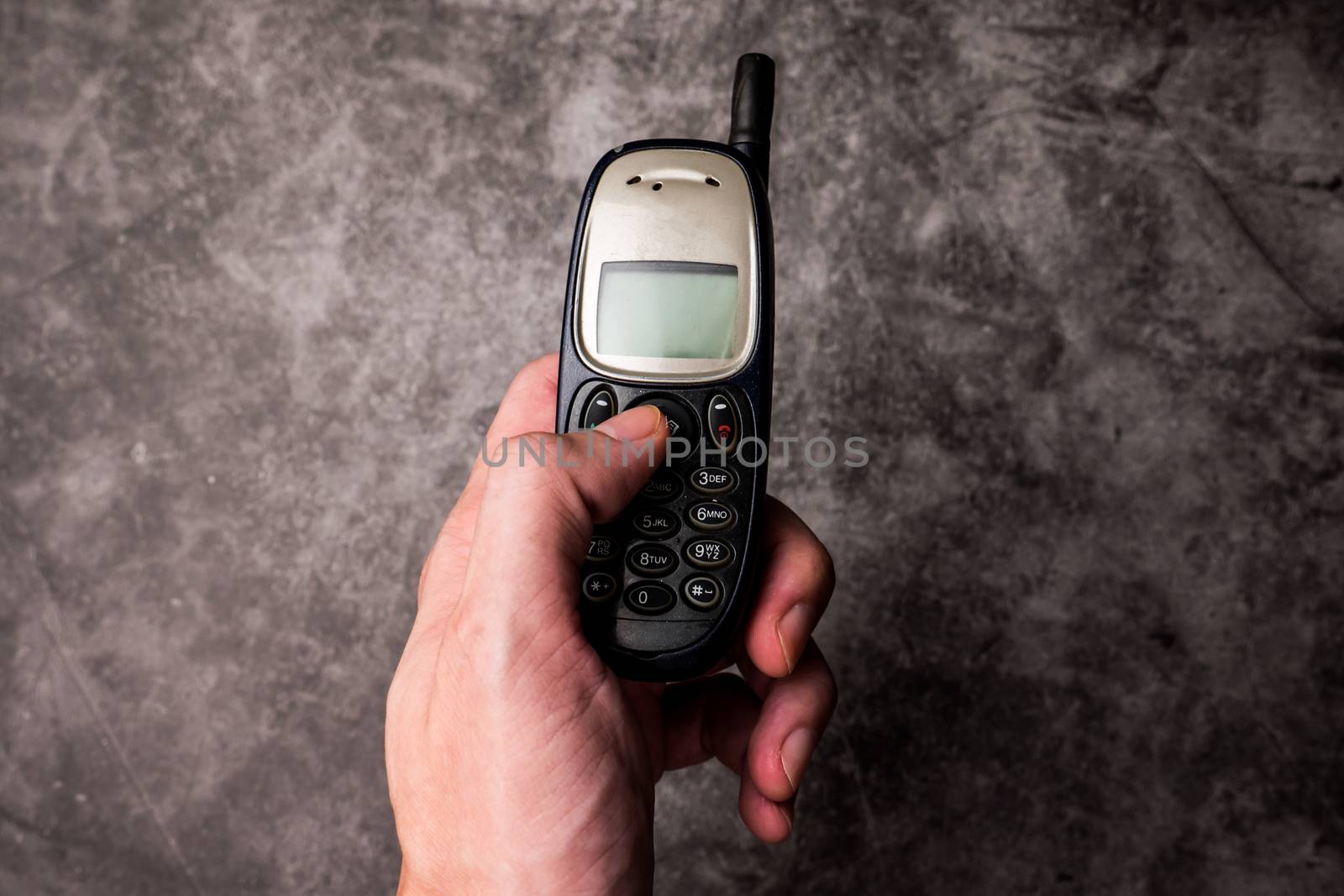 Close up of male hand press on button of an obsolete cellphone.