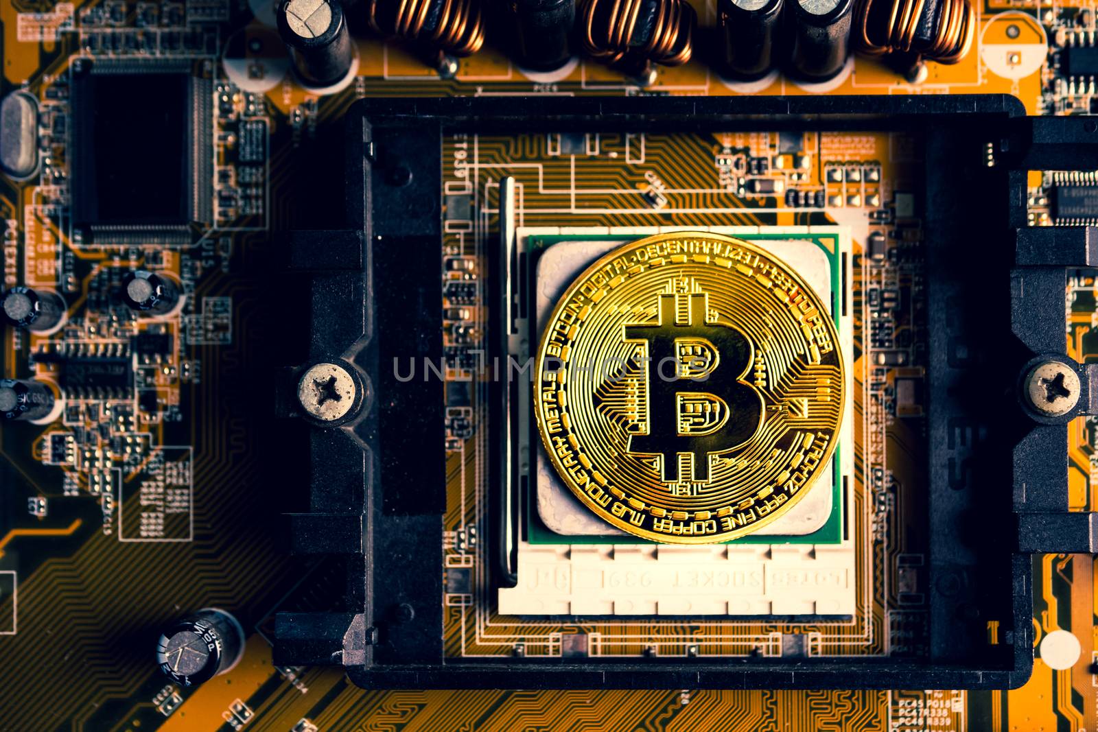 A golden coin with bitcoin symbol on a mainboard.