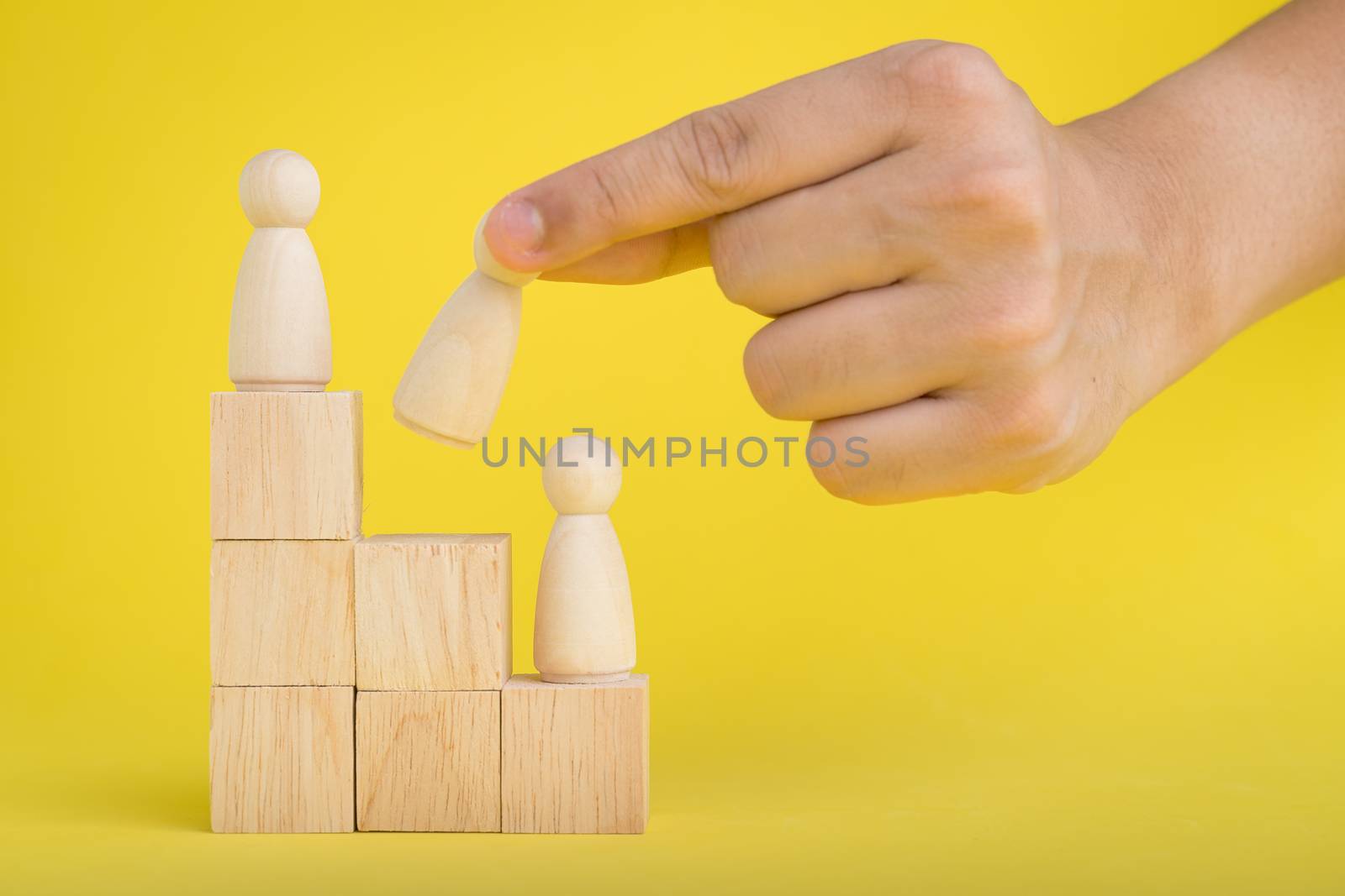 The hand is picking or select wood figure on the wooden Stacked in human resource management concepts Teamwork.Success Leadership,Business Progress and Competition on yellow backgrond and copy space