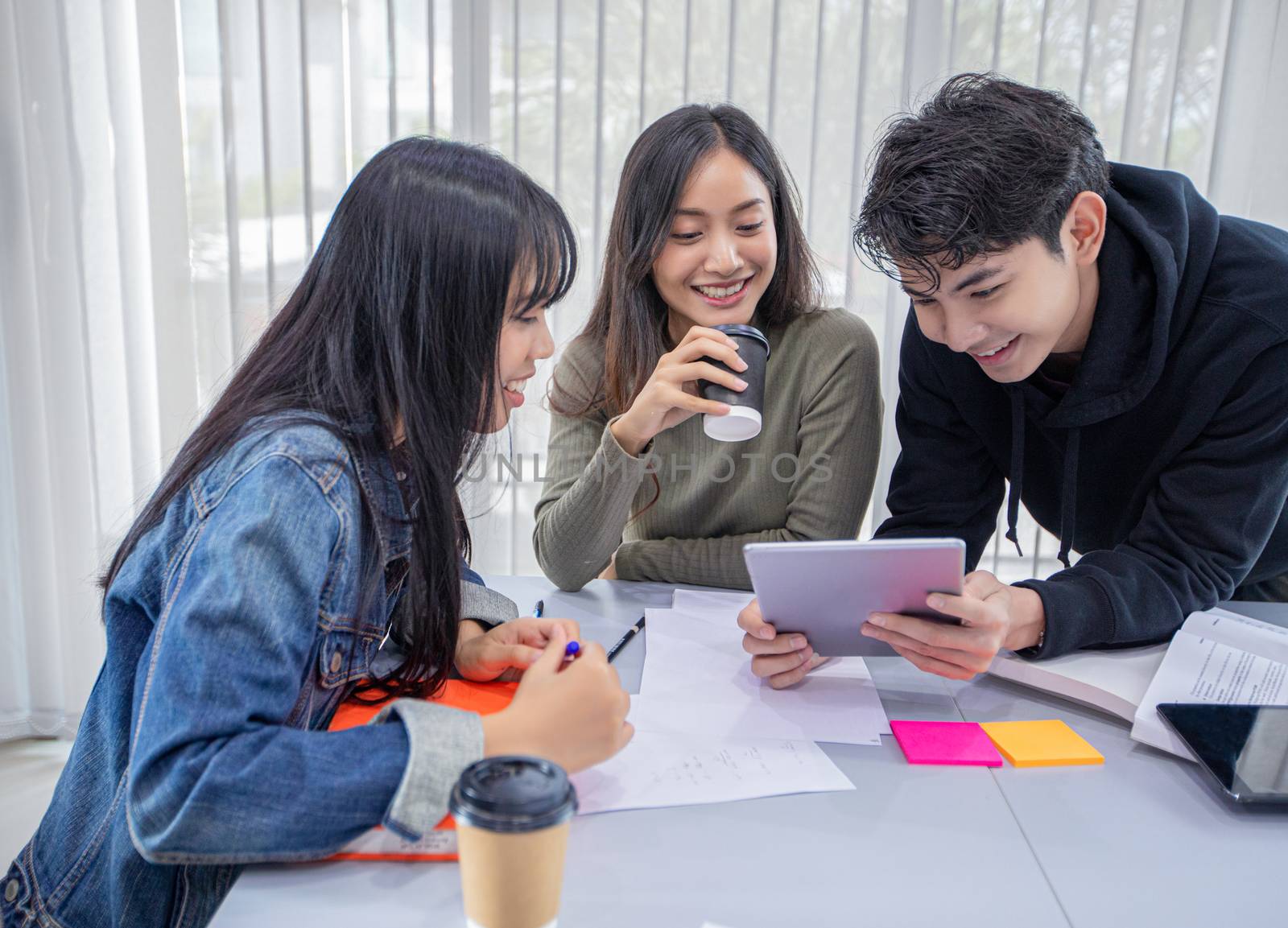 Group Students Smile and have fun and using tablet It also helps to share ideas in the work and project. And also review the book before the exam