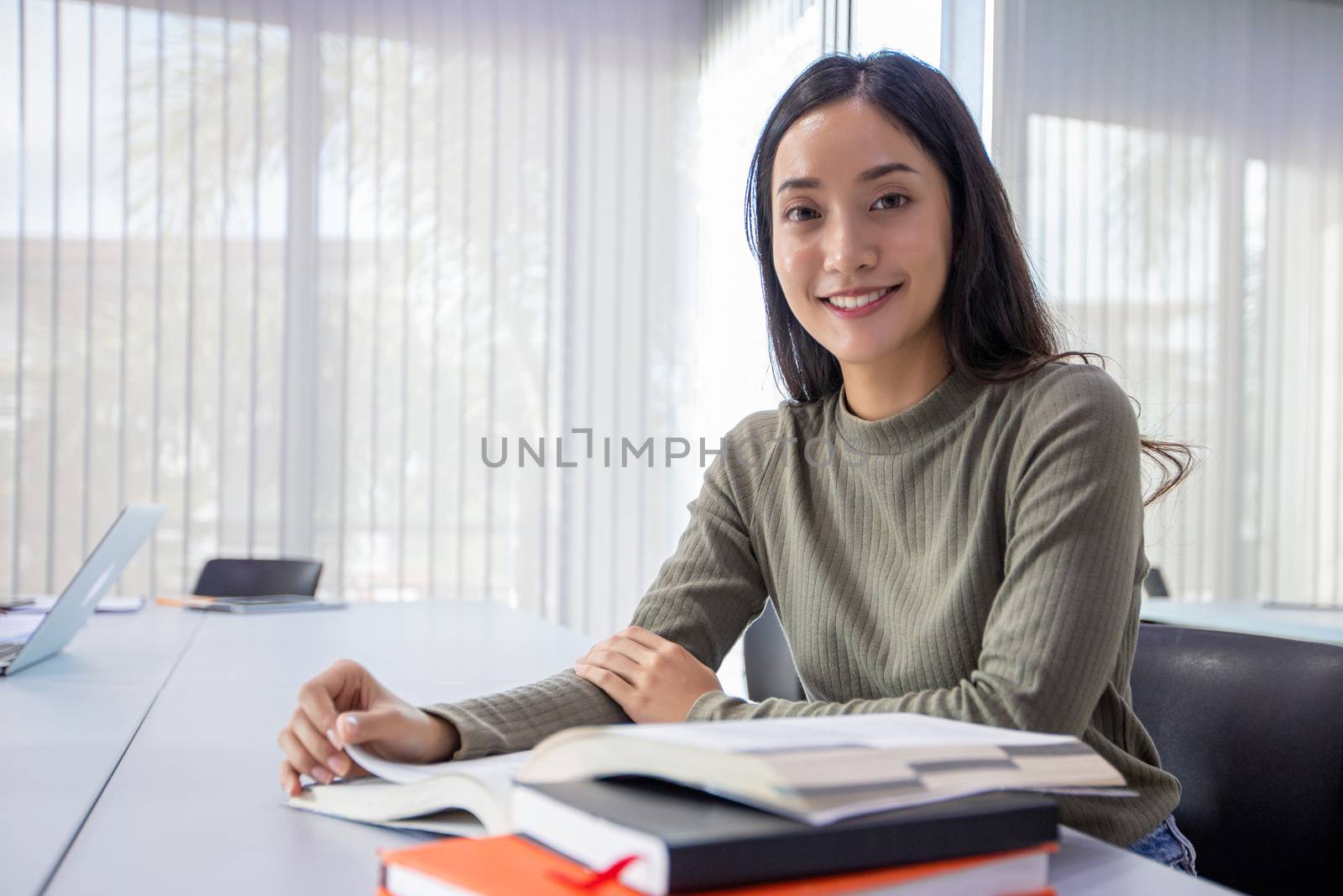 Asian women Students Smile and reading book and using notebook for helps to share ideas in the work and project. And also review the book before the exam