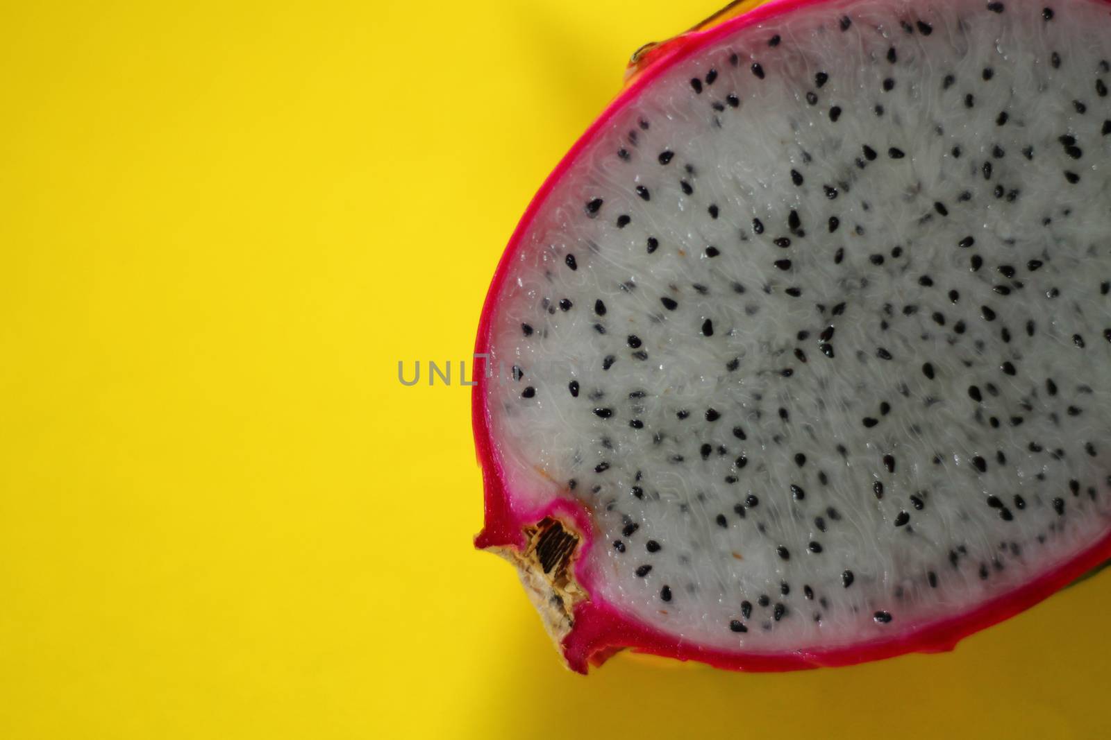 Minimalist tropical summer theme background of a sliced dragon fruit against a yellow background