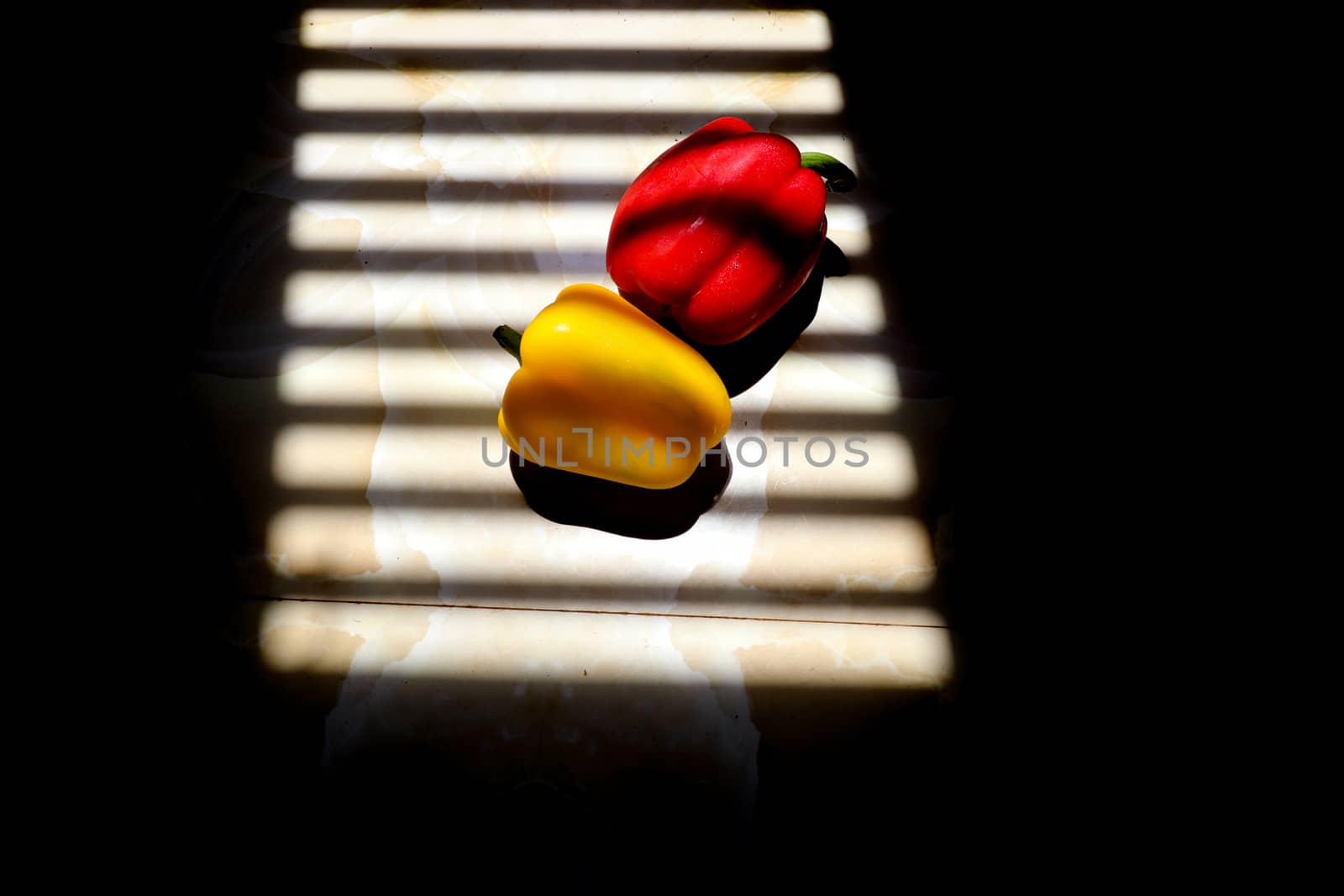Yellow and Red Paprika with with striped shadow lines from a window to show concept of gastronomy, nutrition and veganism