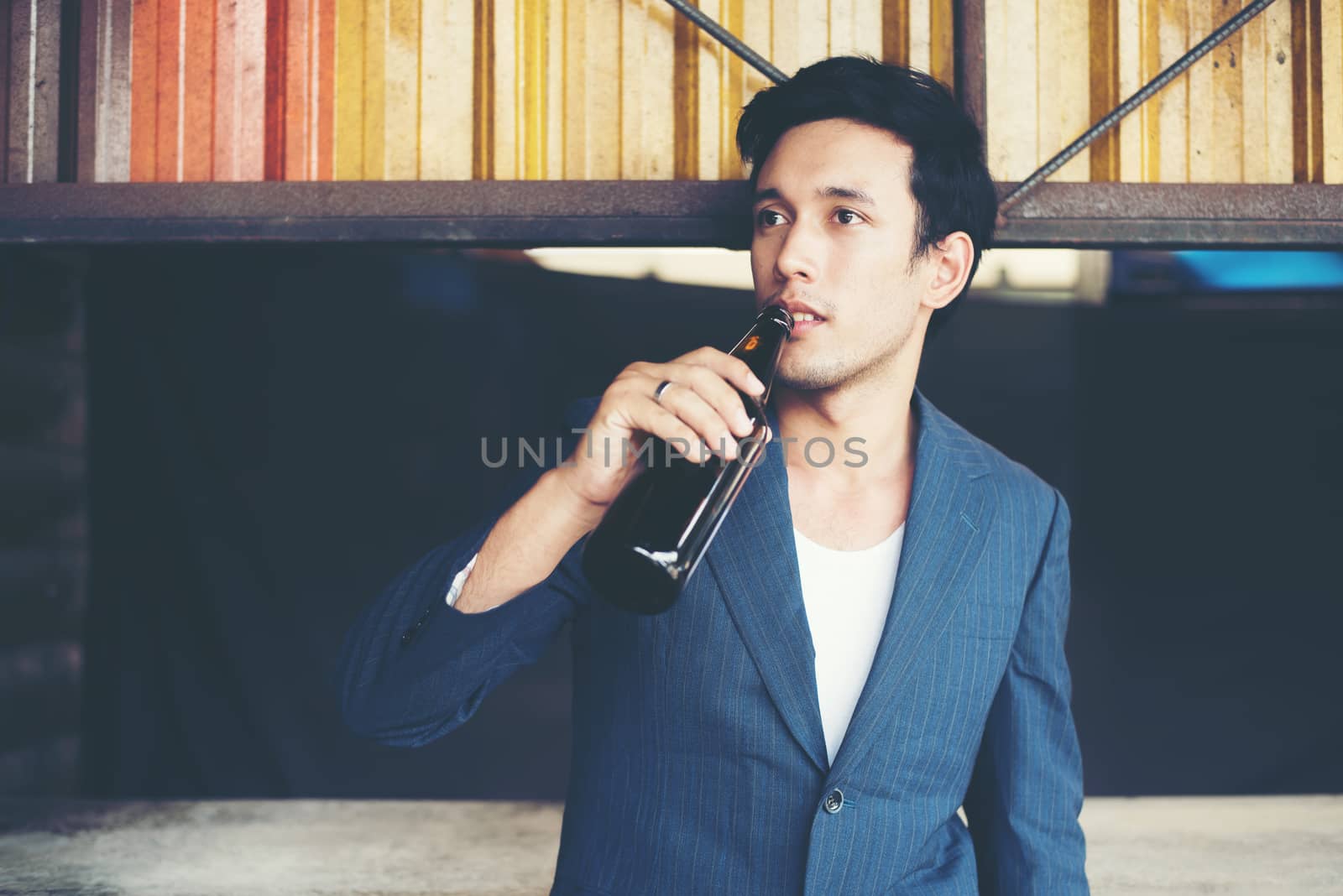 Young handsome businessman drinking beer outside.