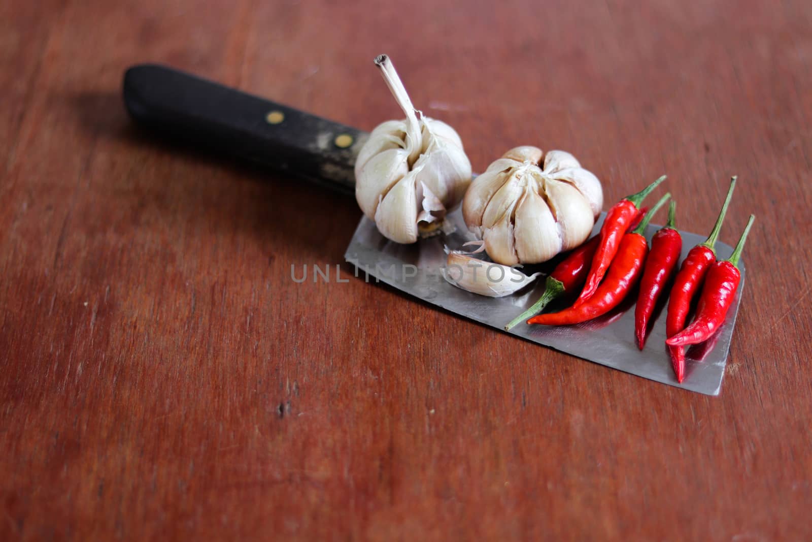 Still life photo of garlic and chilies on a knife to show concept of cooking, cuisine and gastronomy