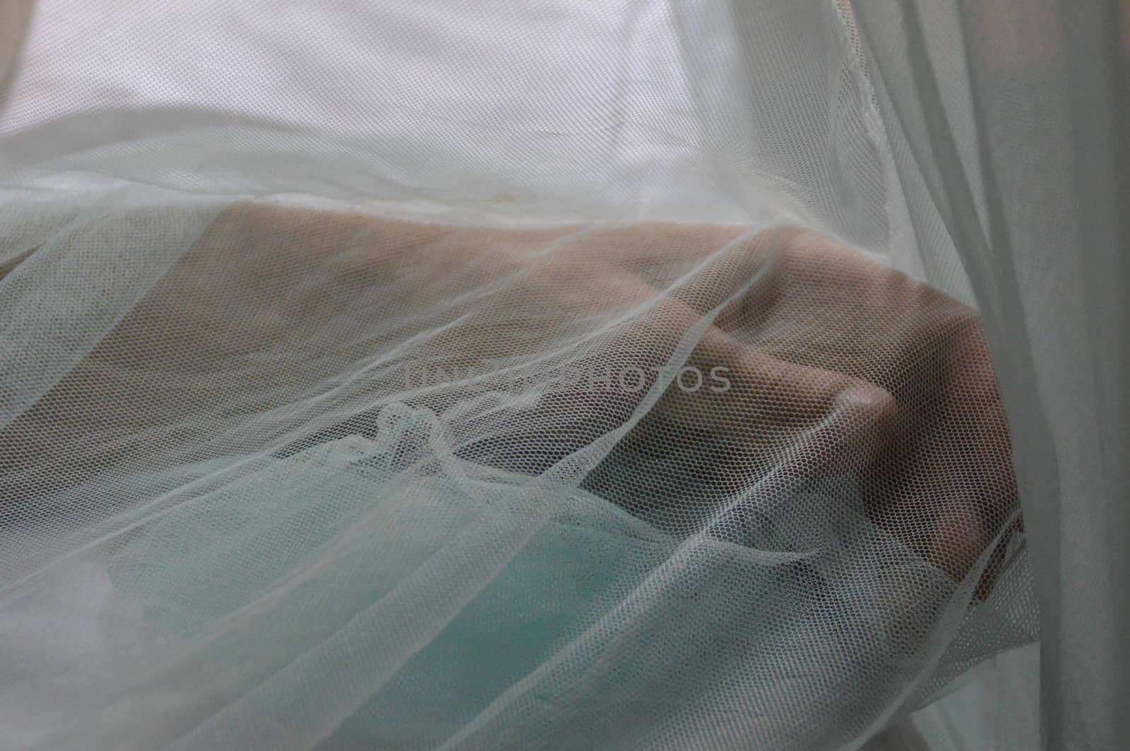 Conceptual photography. Hand covered by delicate light blue veil