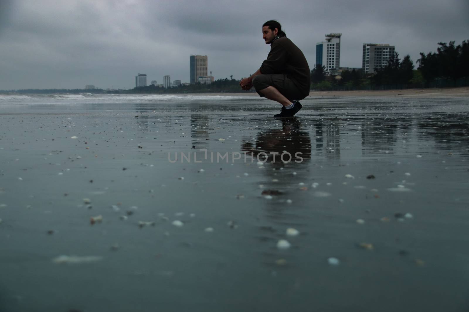 One man looking out into the distance at the shore on a dark gloomy day after a storm