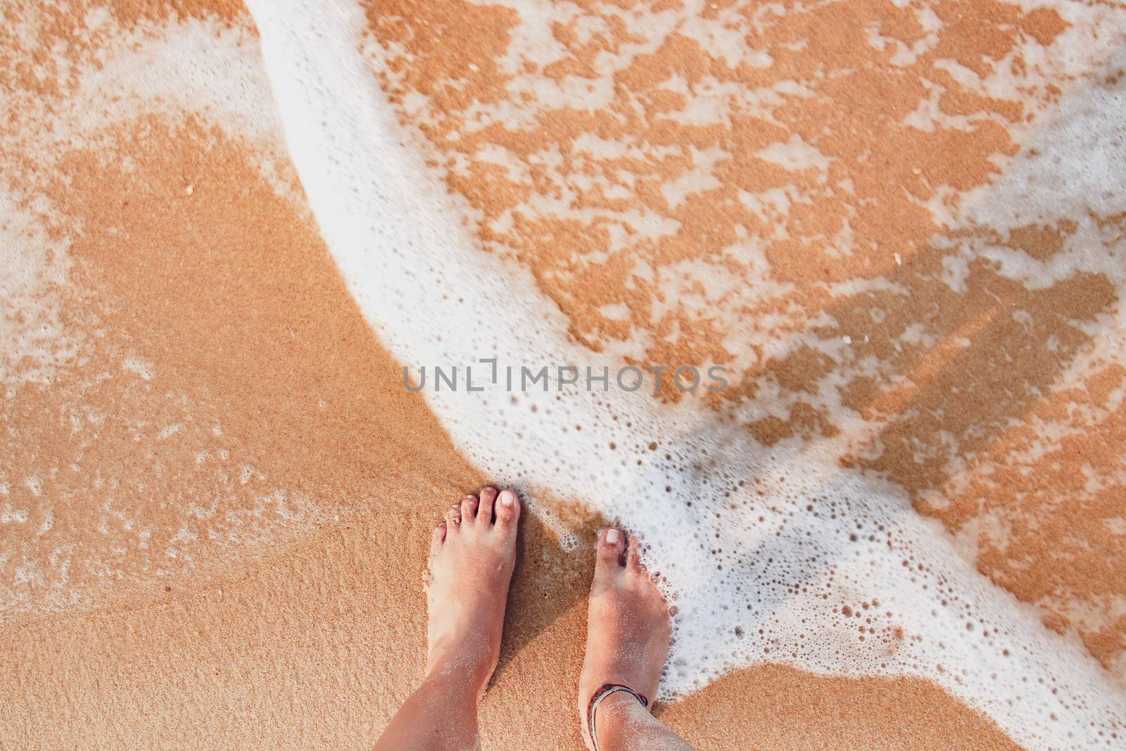 Standing on the beach with feet soaked in the waves showing the summer feeling and being one with nature