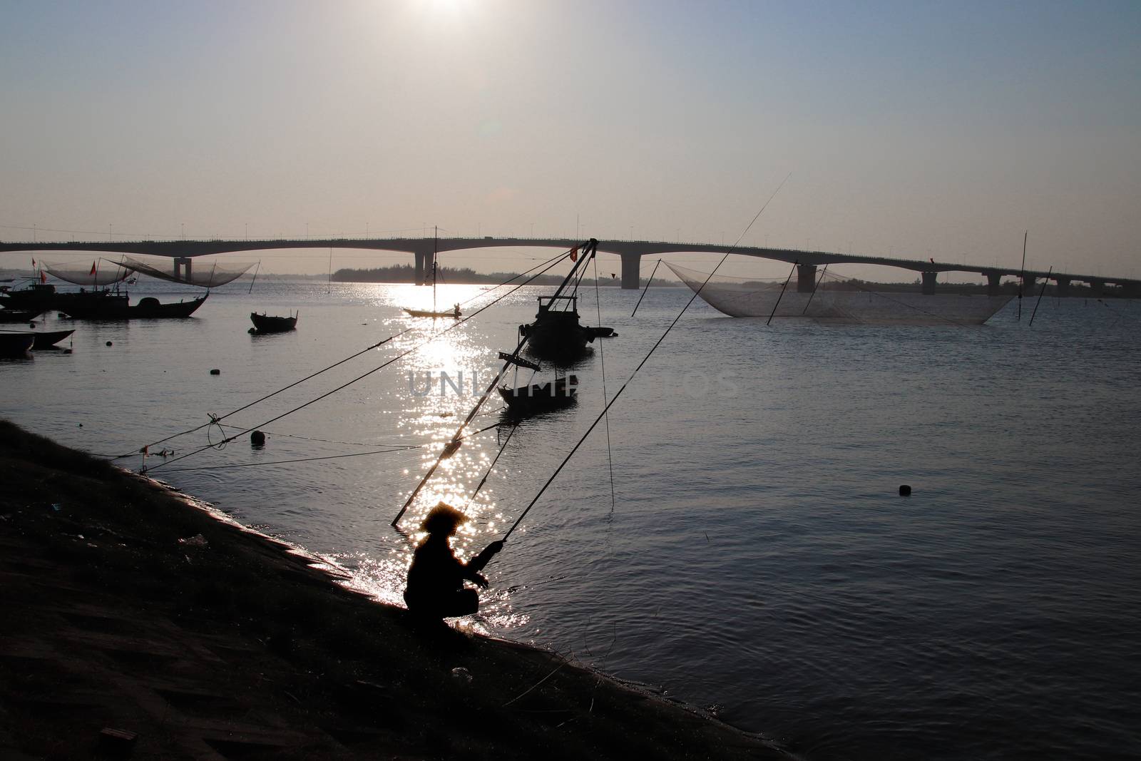 Silhouette of a man pole fishing at dusk in Thanh Nam fishing village in Hoi an, Vietnam