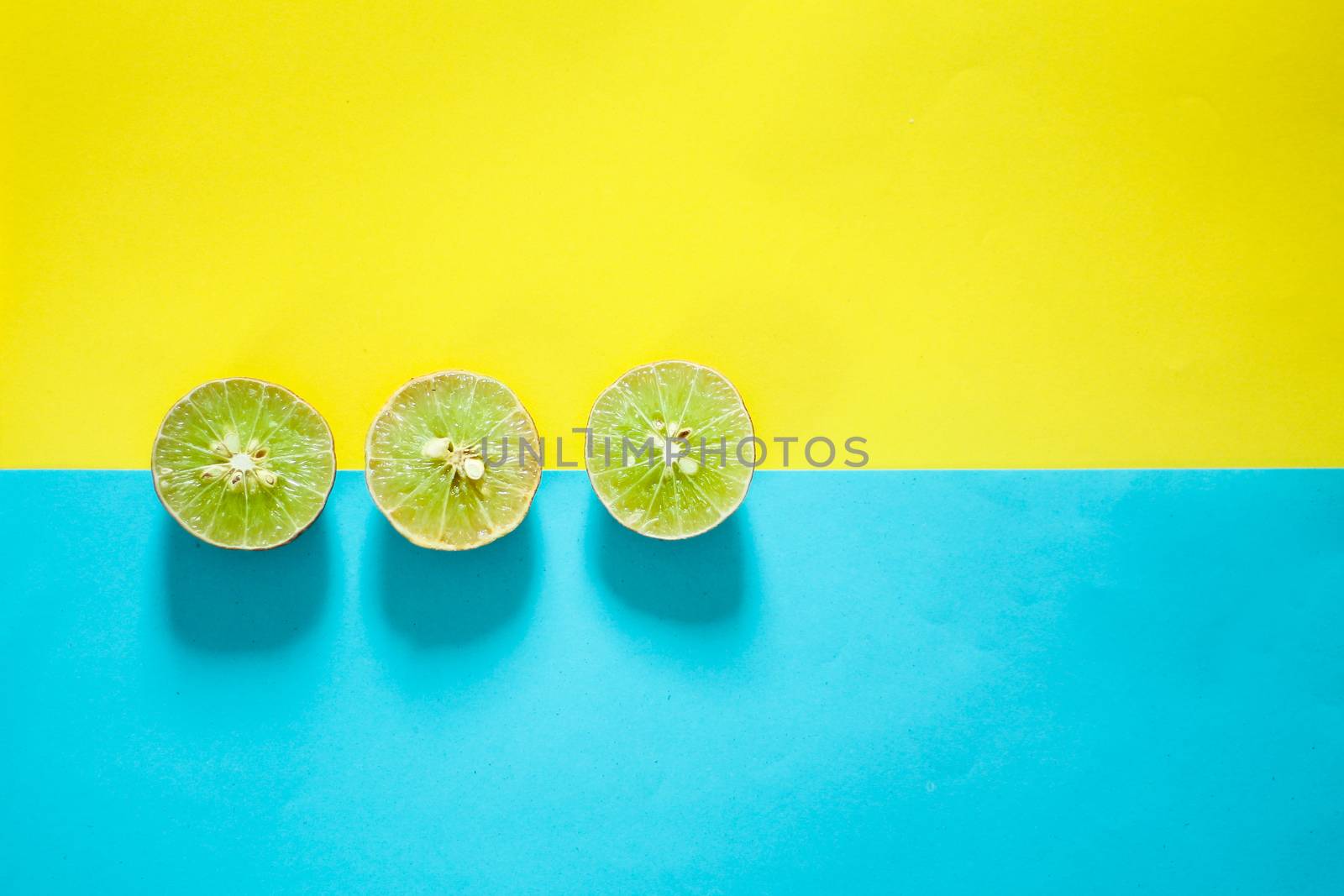 Limes against blue and yellow background by Sonnet15