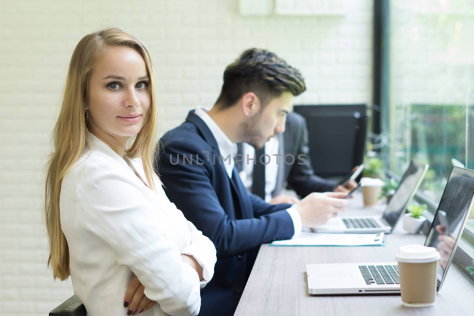 Businesswoman using laptop to work while coworker interacting in the background in the office
