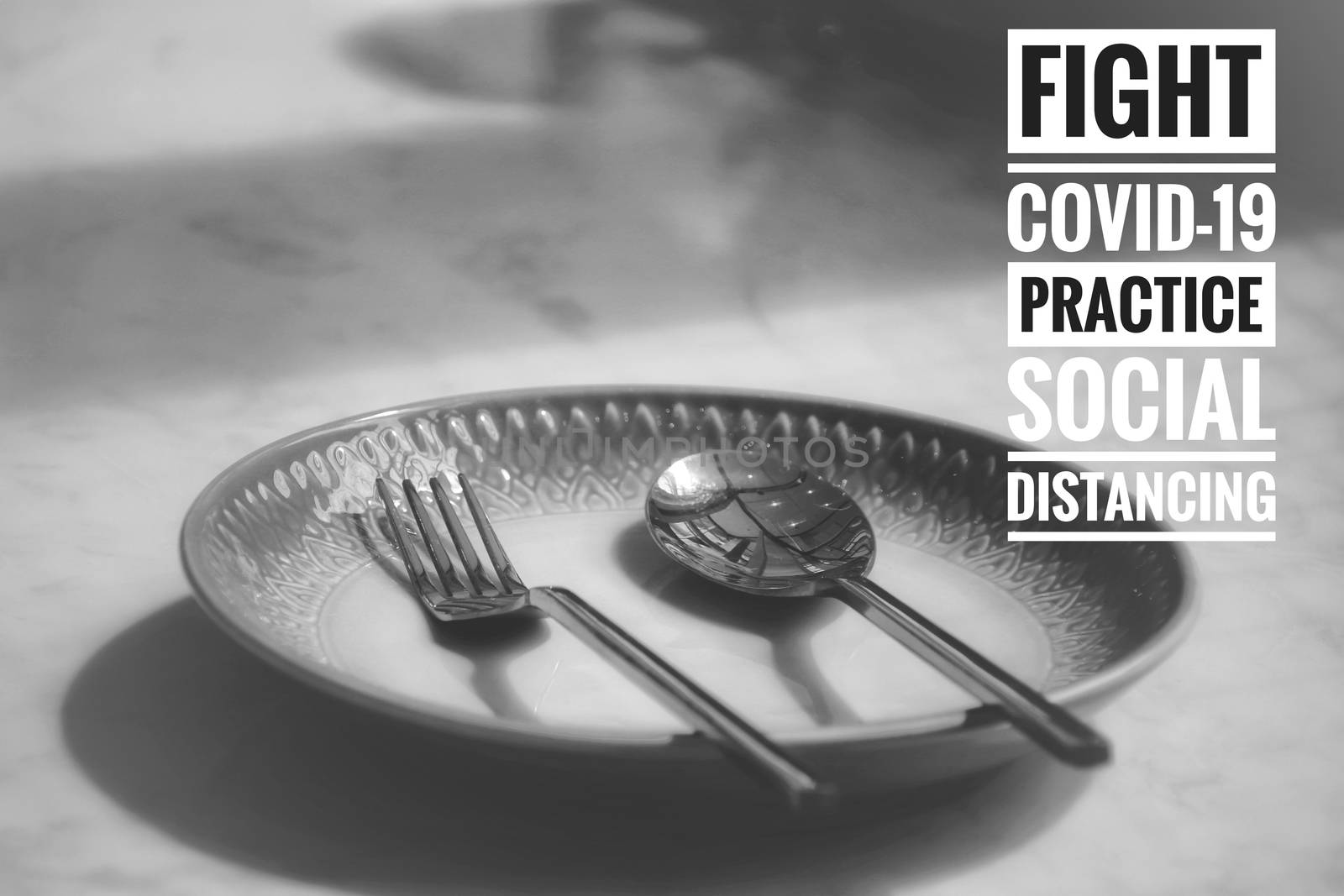 Conceptual still life photo of empty plate with cutlery with the message promoting social distancing, self isolation and home quarantine to prevent the spread of covid-19 pandemic