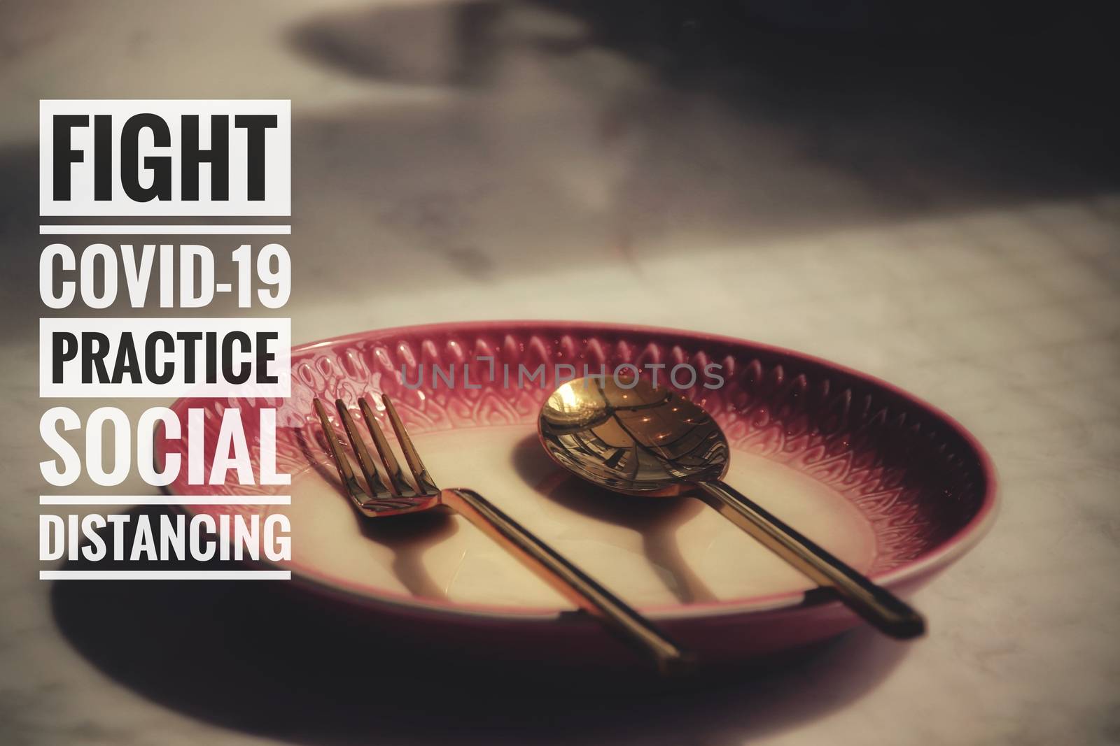 Conceptual still life photo of empty plate with cutlery with the message promoting social distancing, self isolation and home quarantine to prevent the spread of covid-19 pandemic
