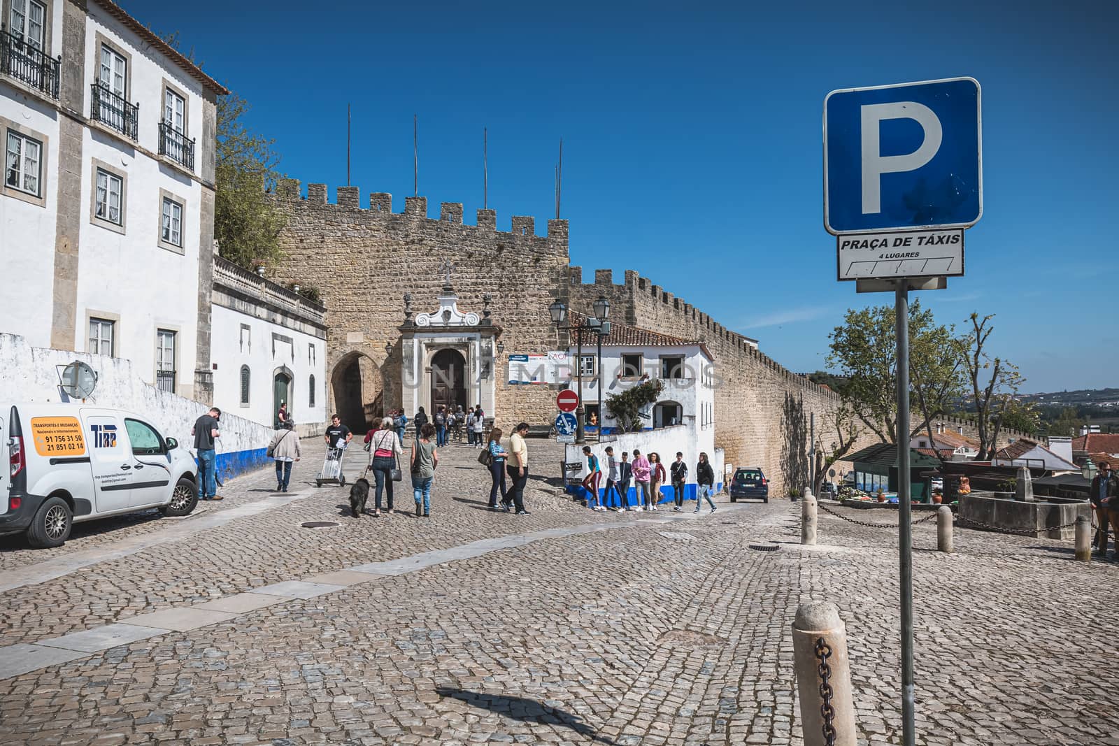 Obidos, Portugal - April 12, 2019: Tourists walking towards the entrance gate of the historic city on a spring day