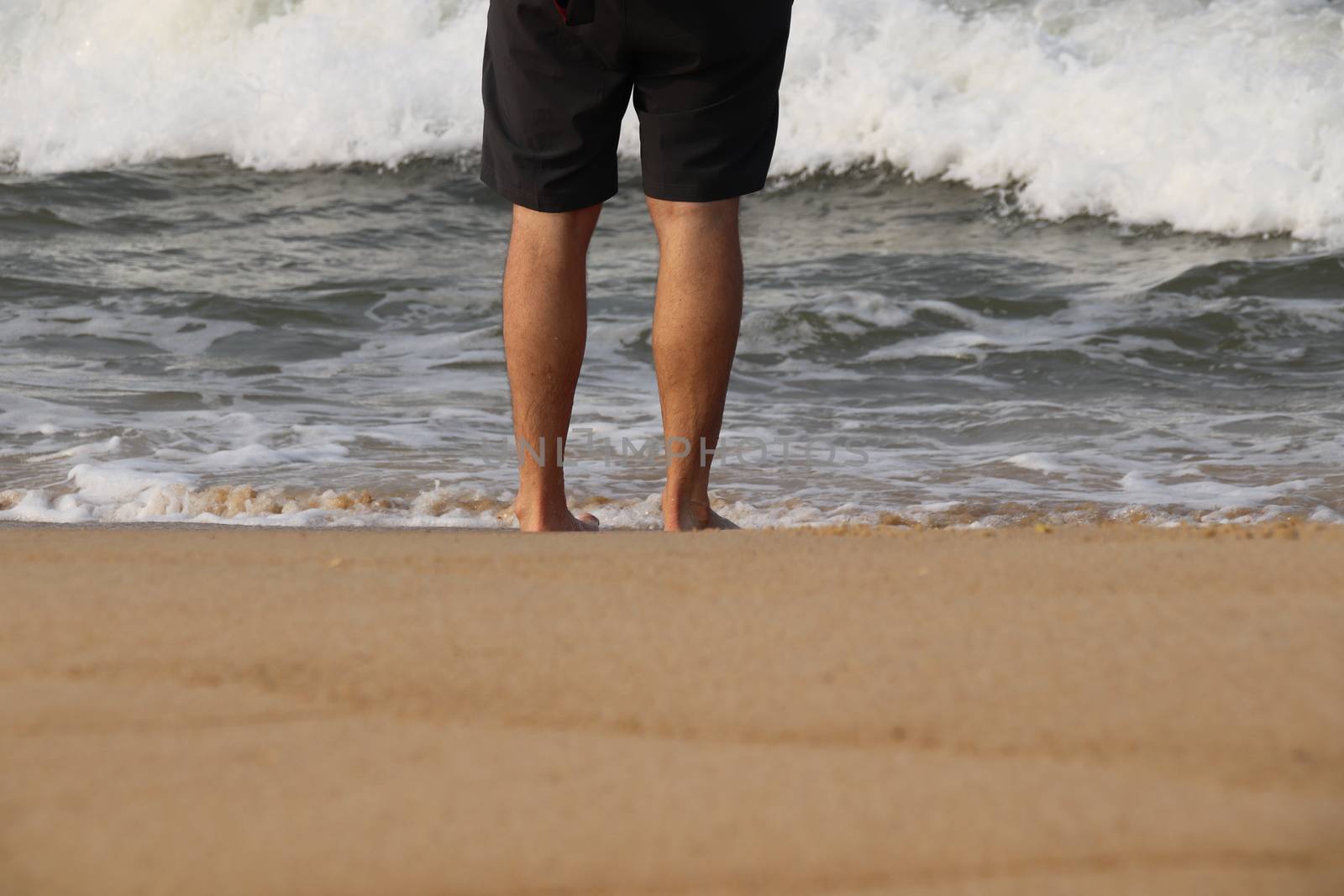 Low section of a man walking on the beach