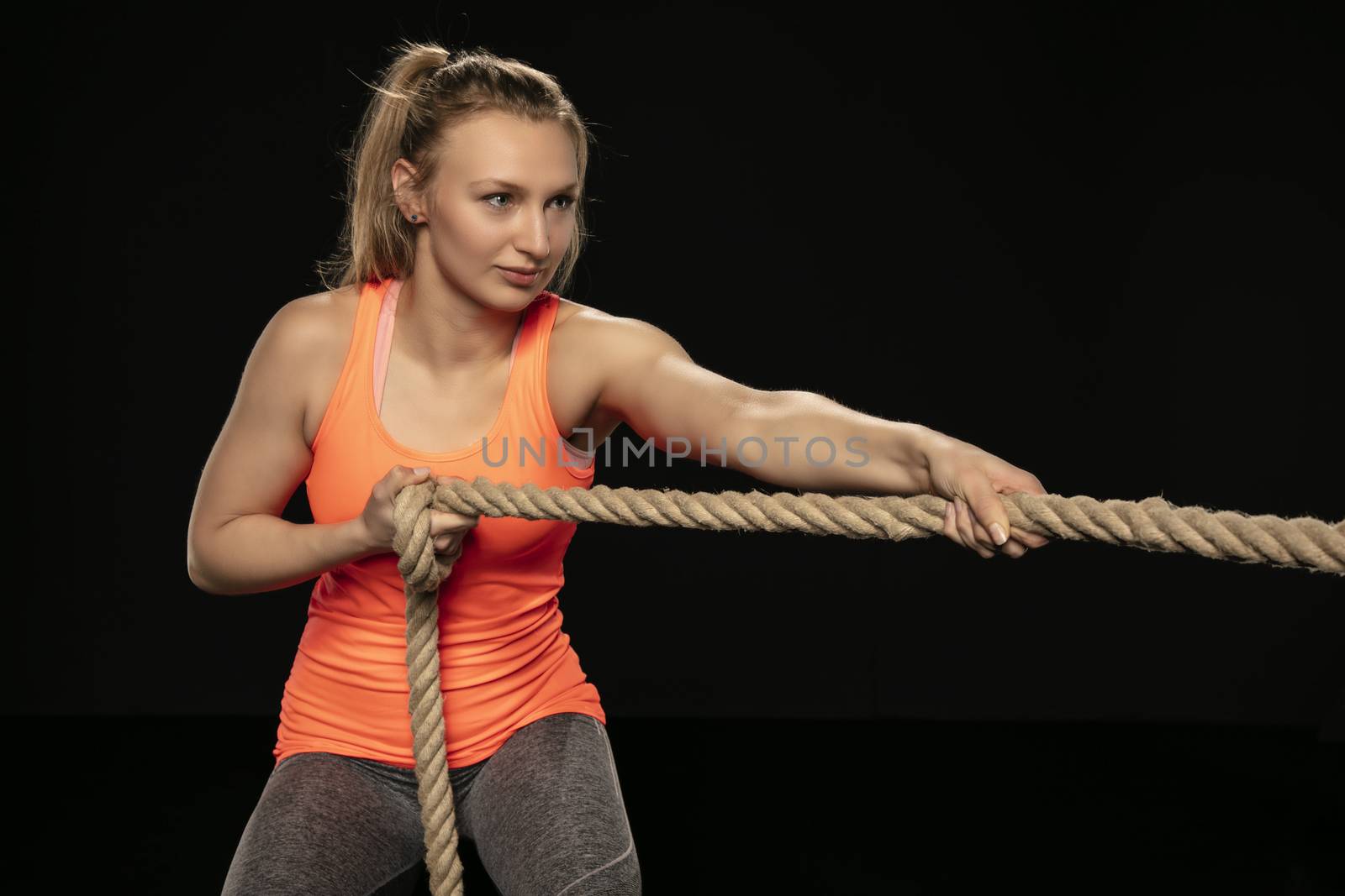 athletic girl exercising with a thick rope