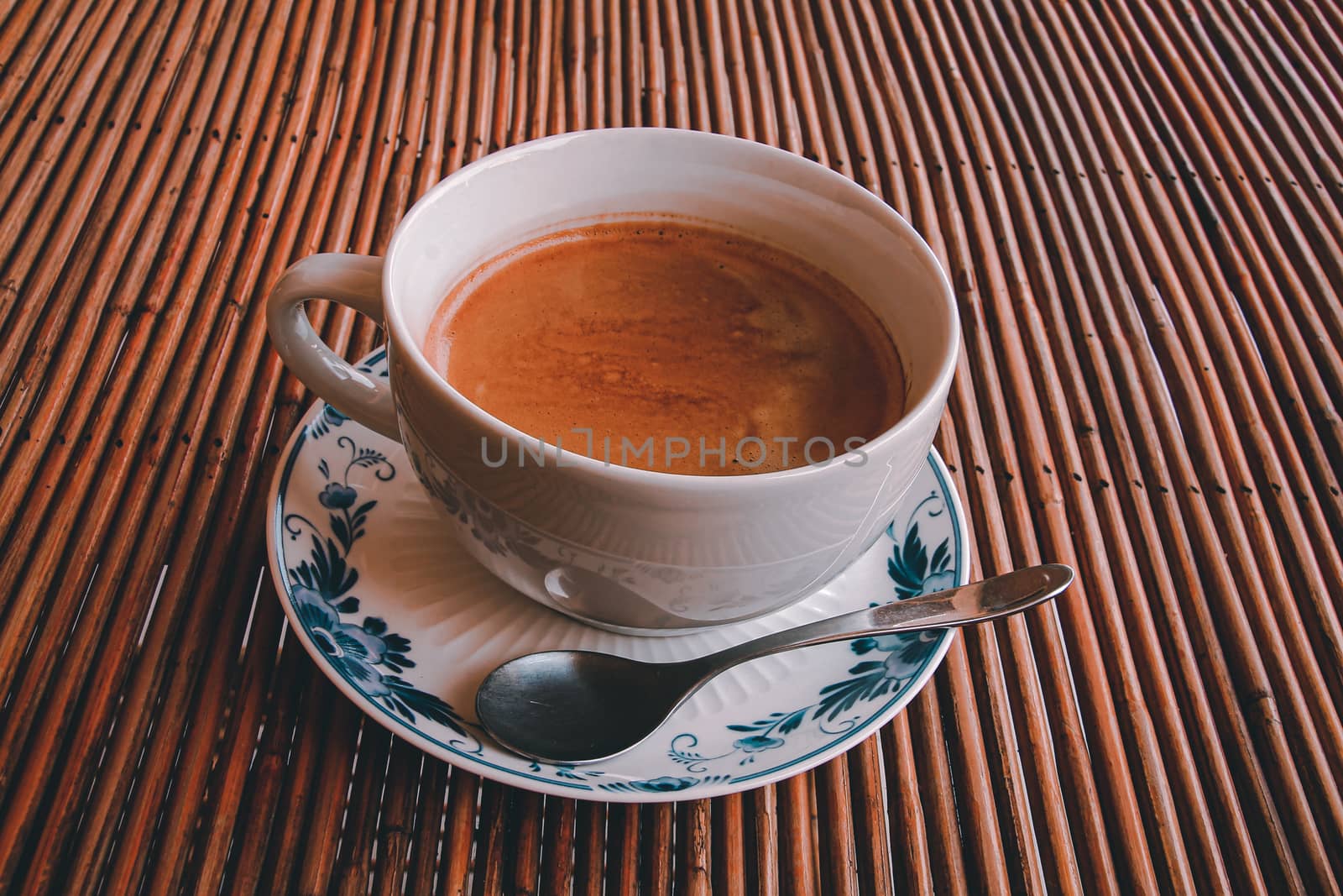 Conceptual photo of a single cup of coffee against a wooden table to show concept of self isolation and social distancing as the new normal during the covid-19 pandemic