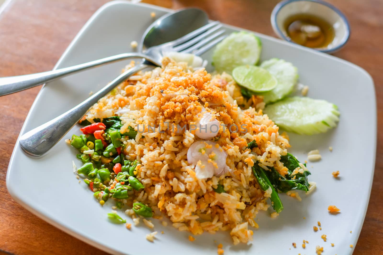 Delicious Thai food. Fried rice with egg, Kale served with minced red and green chilli in white plate on wooden table in cafe and restaurant. Selective focus.