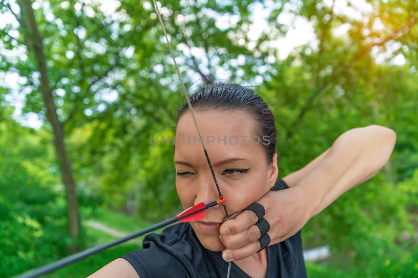 archery, young woman with an arrow in a bow focused on hitting a target.