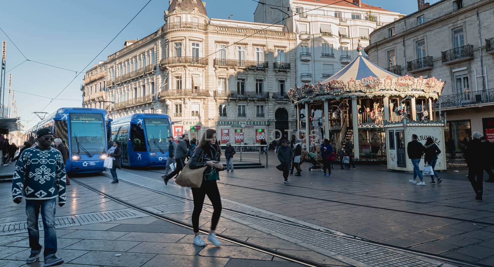 Montpellier, France - January 2, 2019: Electric tram stopped at Place de la Comedie where people pass on a winter day