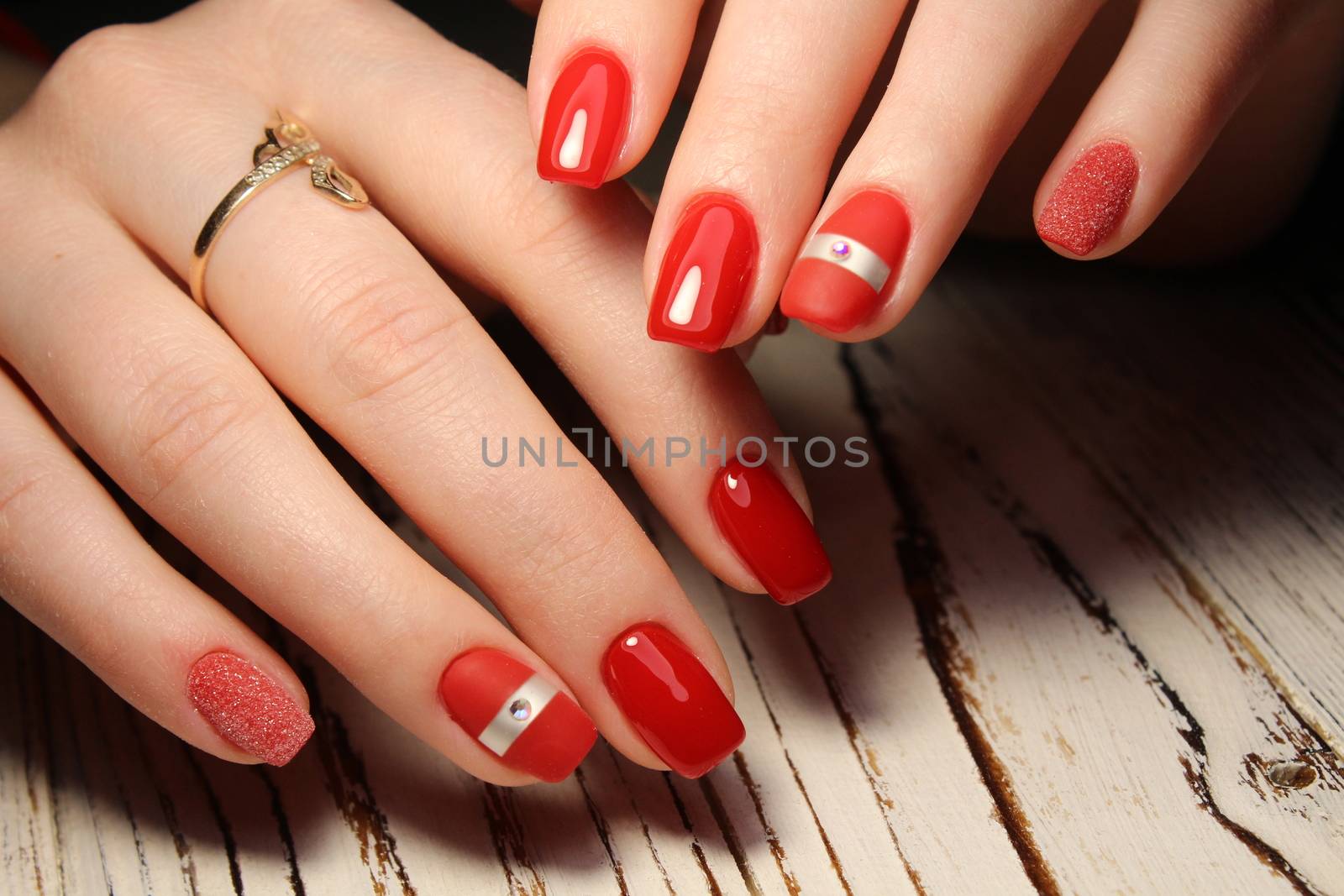 Hands with long artificial manicured nails colored with red nail polish