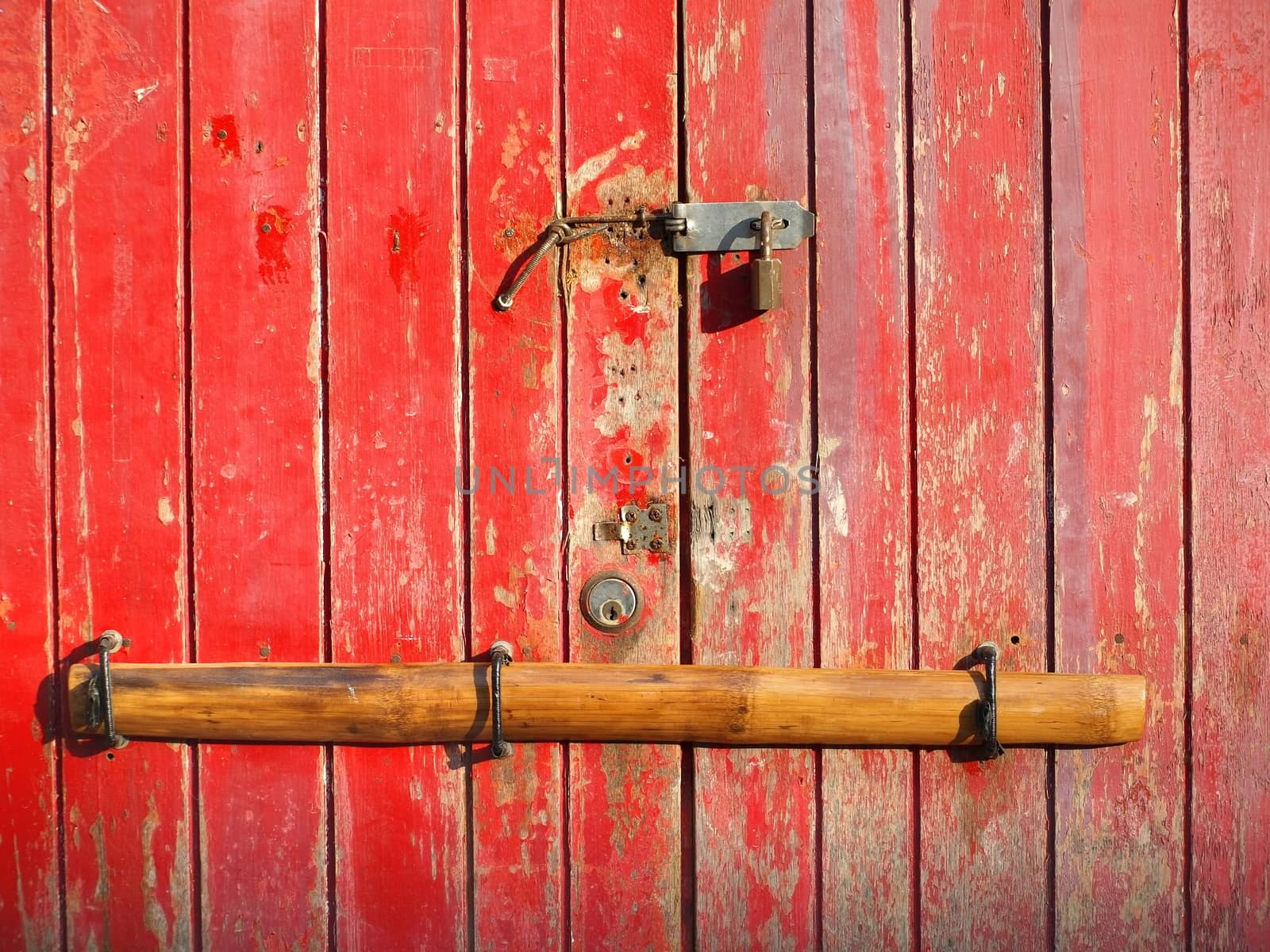 An old Chinese door that is barred with a bamboo pole
