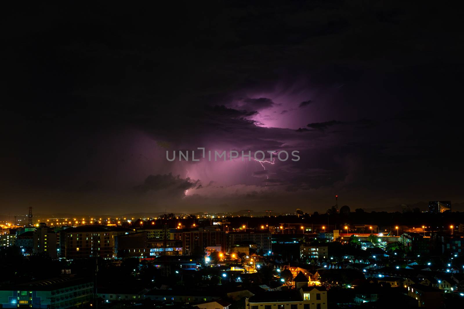 Cloudy with Bright lightning bolt strikes in the rural landscape of small city by peerapixs