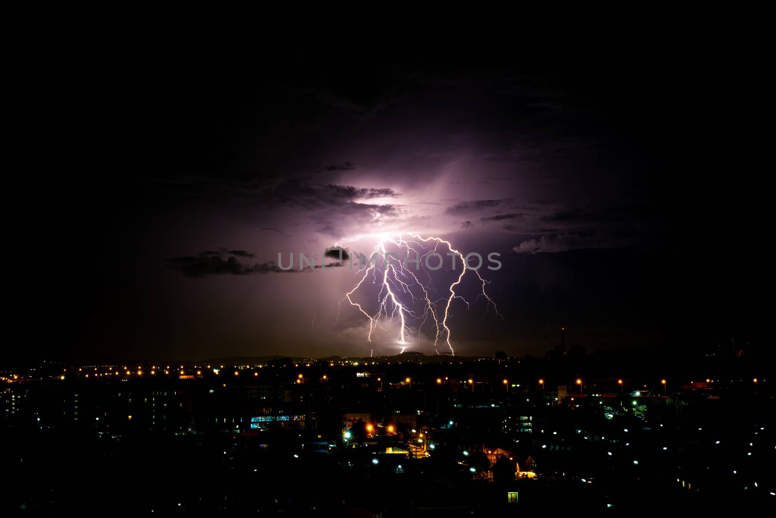 Cloudy with Bright lightning bolt strikes in the rural landscape of small city by peerapixs