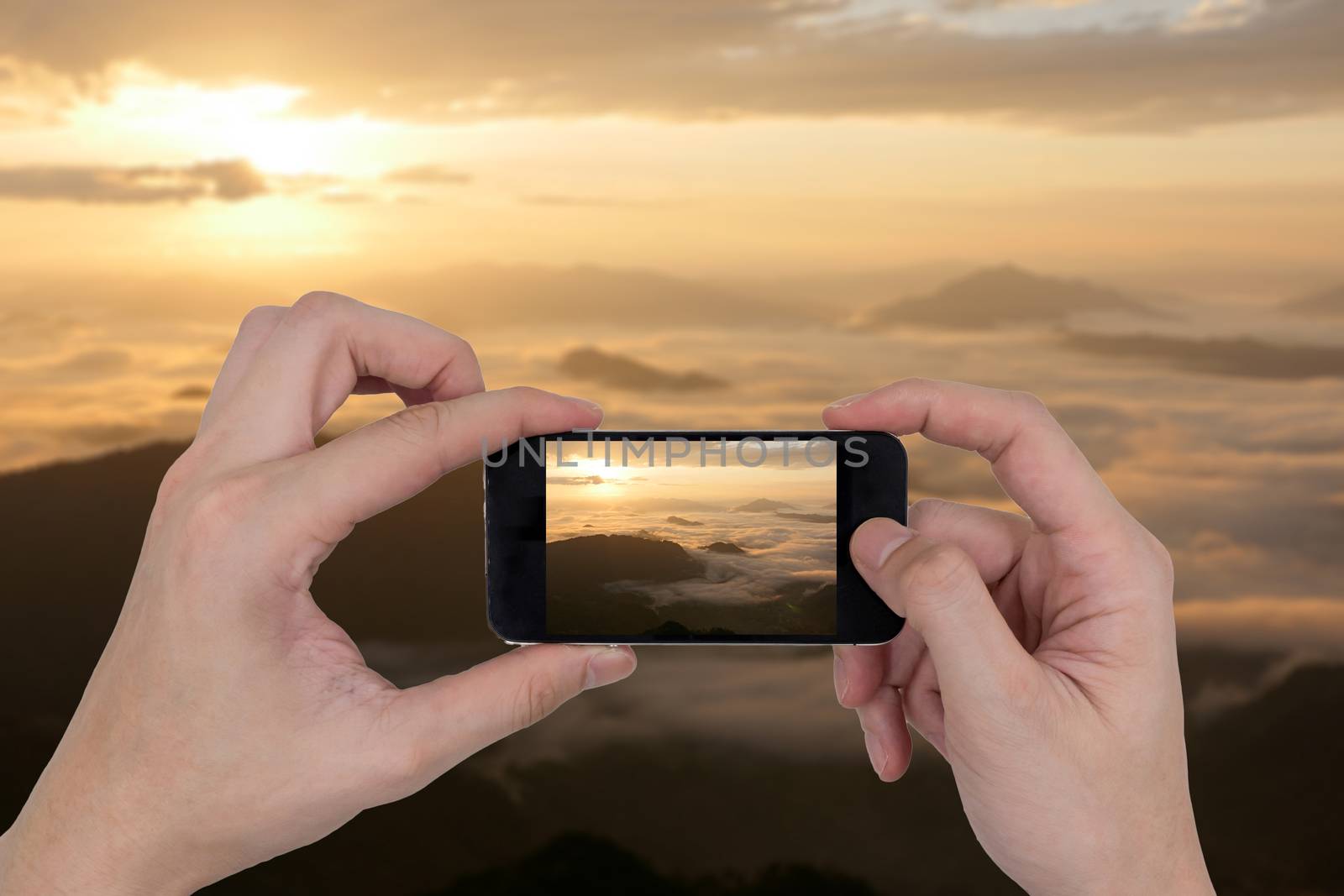 Male hands holding smartphone taking picture of mountain landscape.