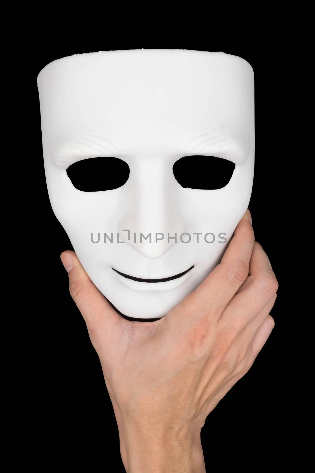Hand holding white mask on black background.