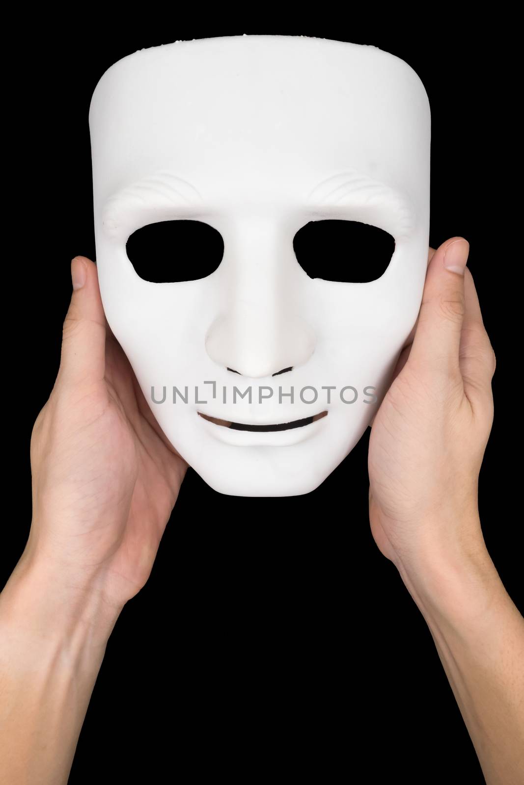 Hands holding white mask on black background.