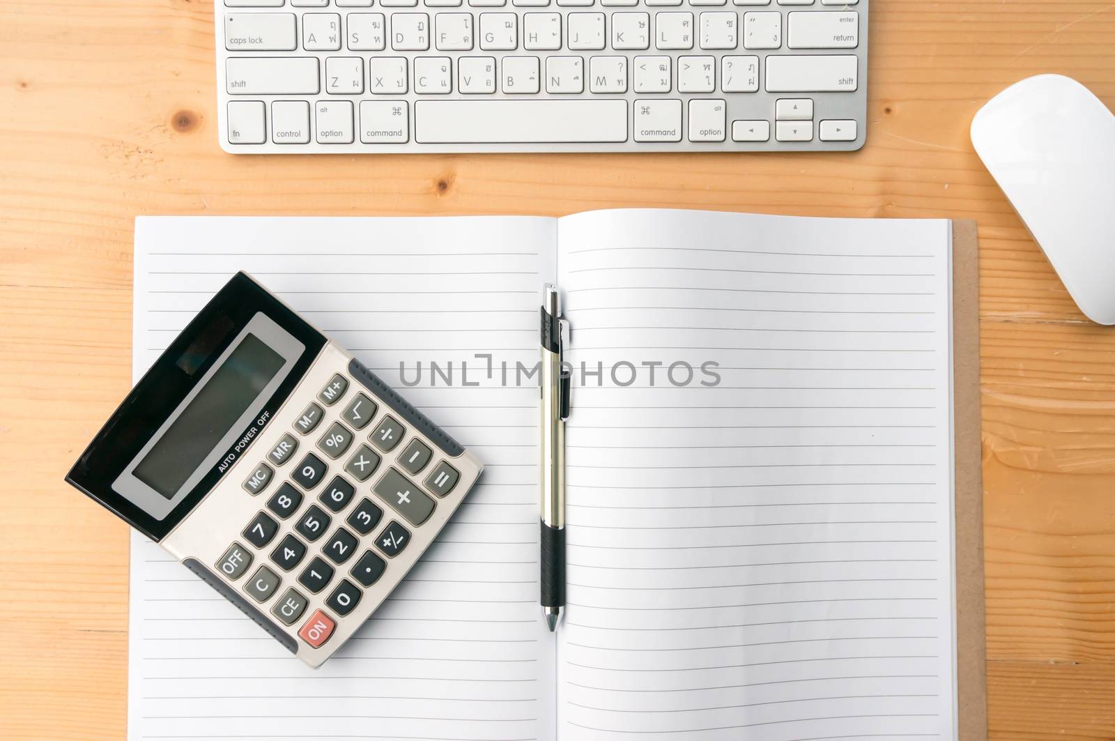 Top view workspace with blank notebook,pen,calculator keyboard aand mouse on wooden table background. by ronnarong